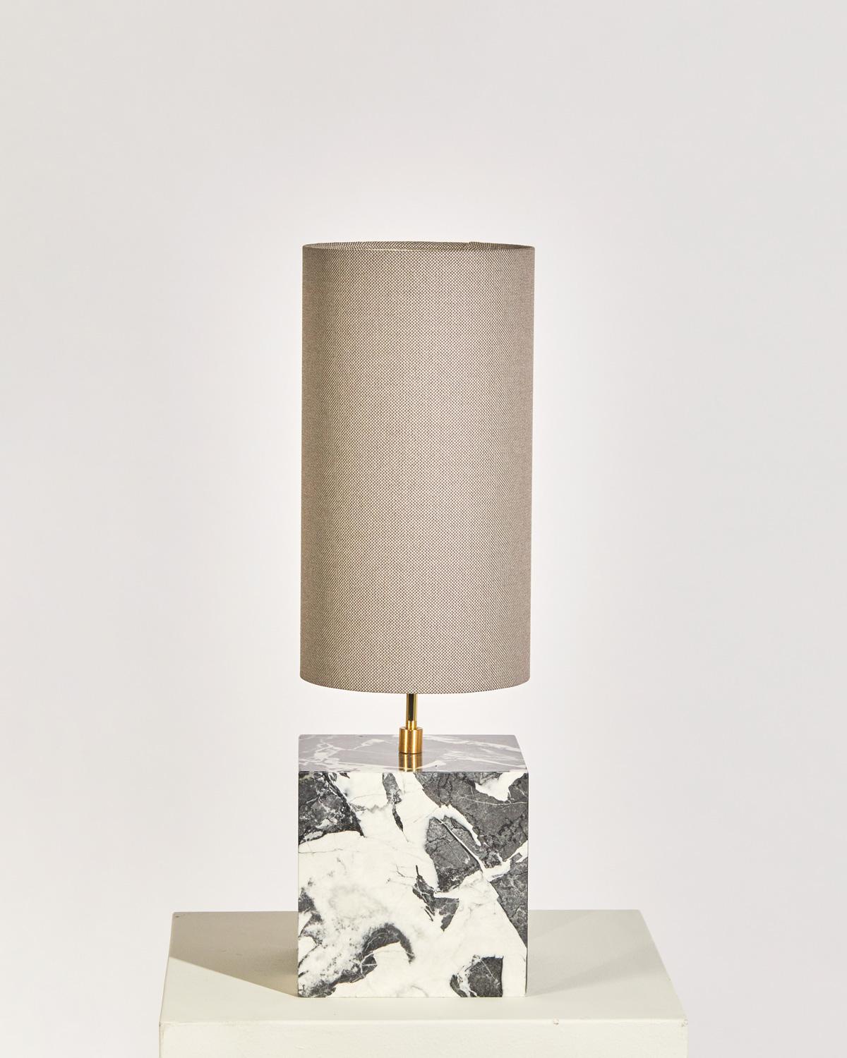 Die Coexist Tischleuchte besteht aus einem Marmorwürfelsockel und einem Lampenschirm aus recyceltem Stoff.

Die Leuchte dient als skulpturaler Mittelpunkt eines jeden Raumes und strahlt ein weiches, warmes Licht aus, das den Betrachter in die