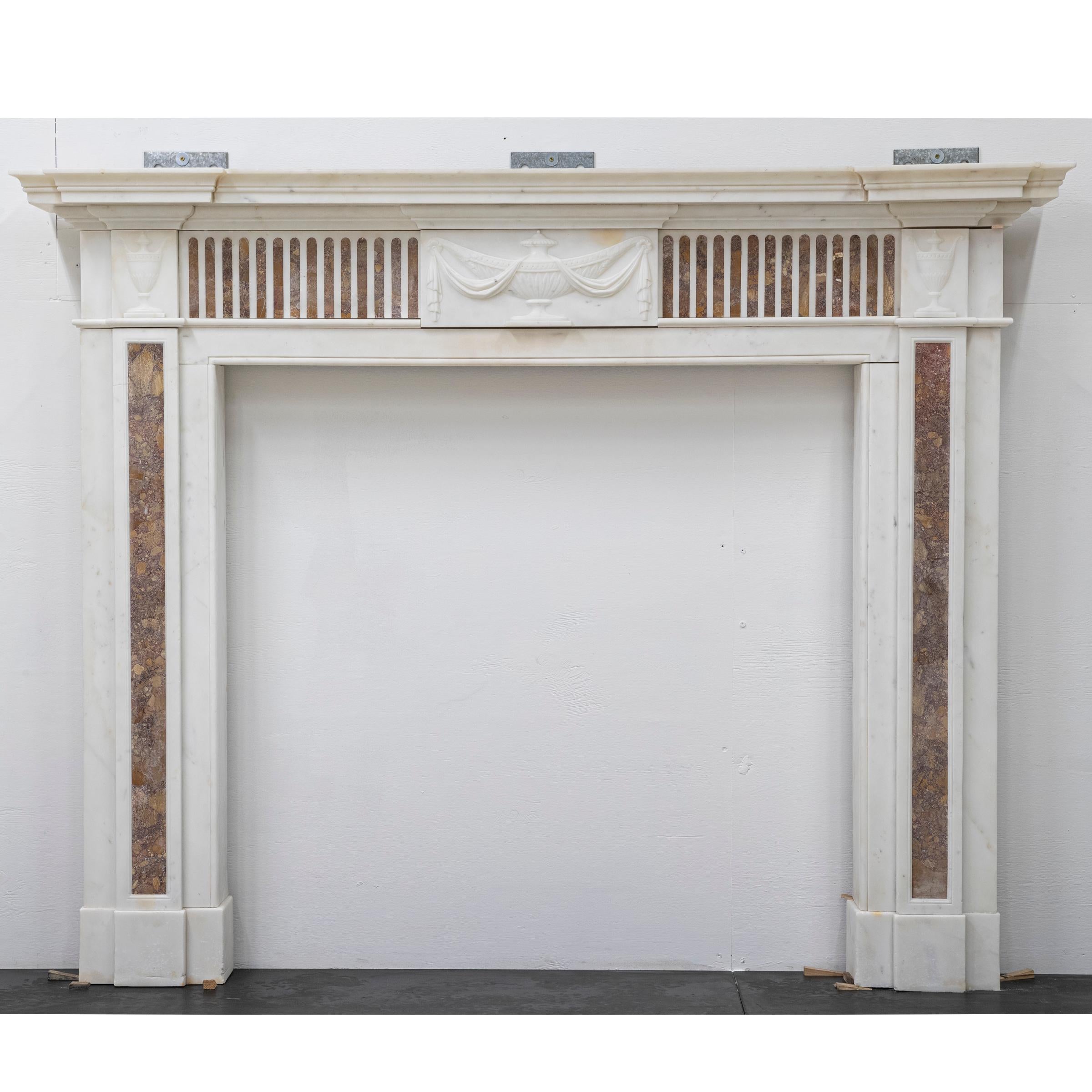 A fine, late Georgian chimneypiece in Statuary marble with Spanish Brocatelle marble fluting and ingrounds.

The breakfront shelf rests above an opulent frieze that is decorated with thumbnail Brocatelle marble. The frieze is flanked by end blocks