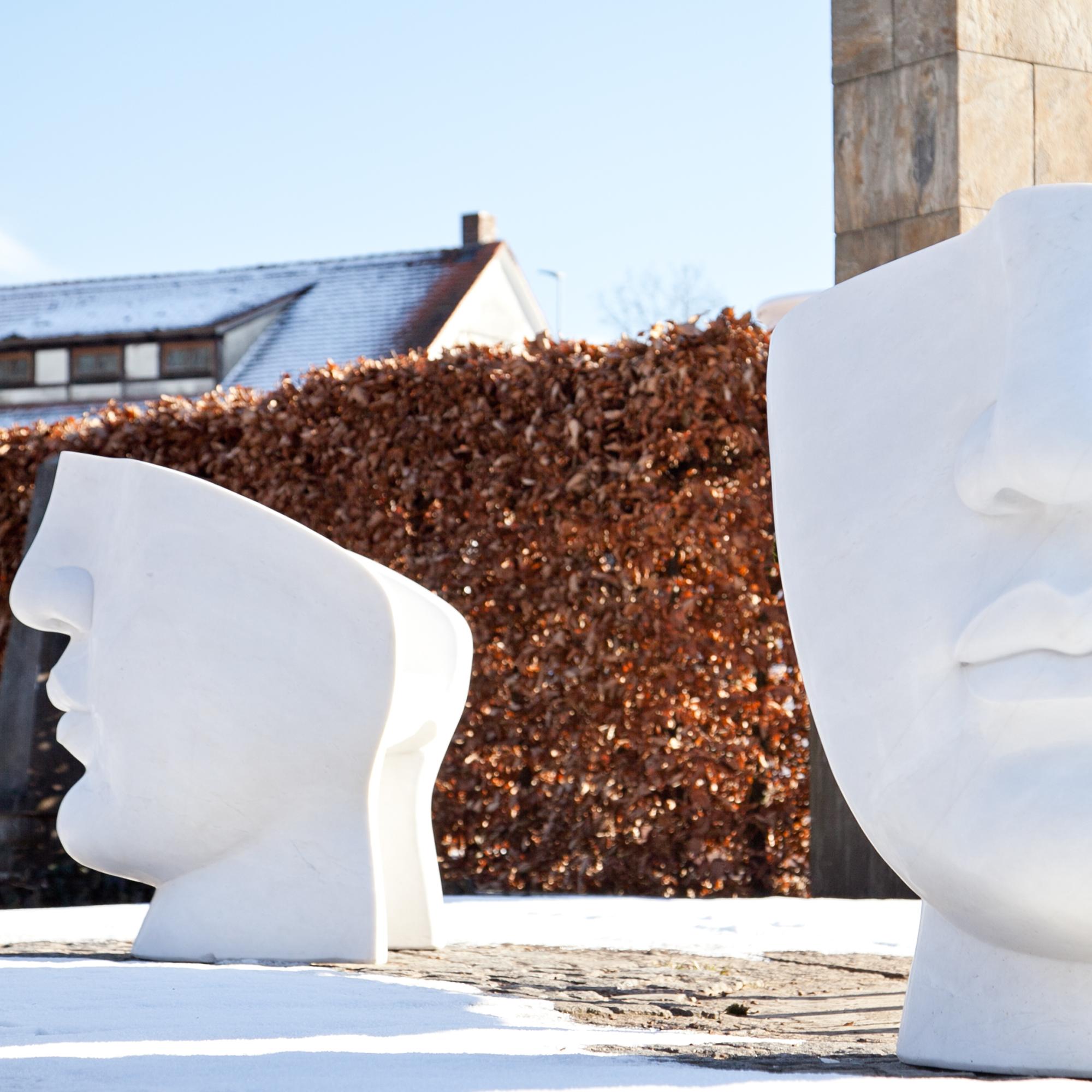 Pair of large hand-carved armchairs out of marble and a backrest shaped like a face.