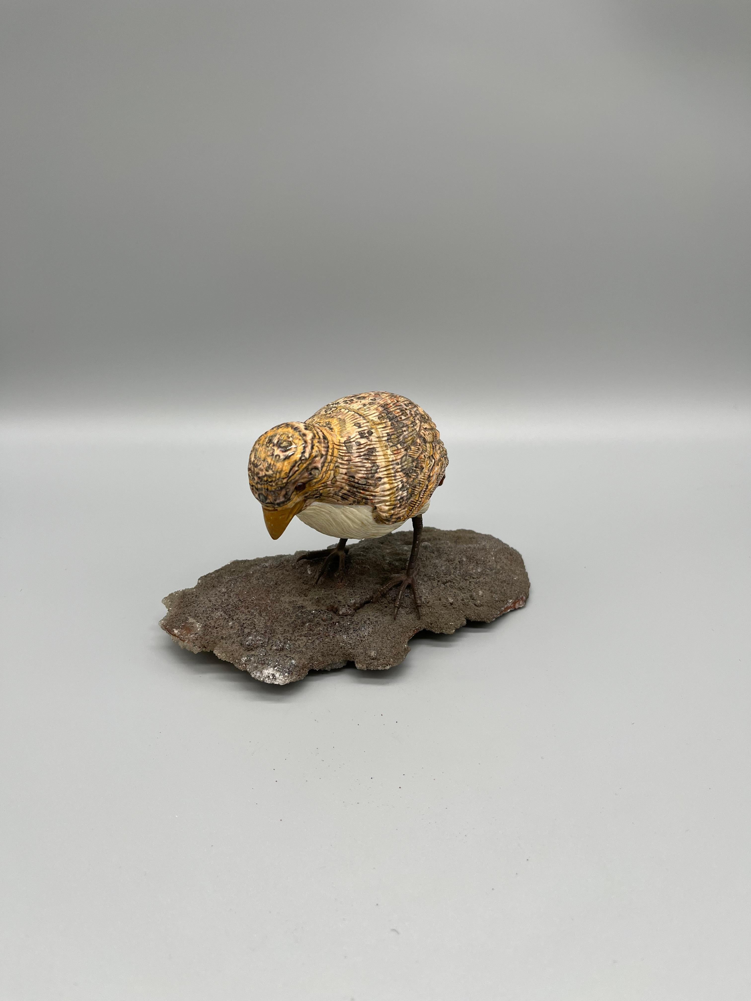 Carved marble bird with ruby eyes resting on a rock with crystals, 20th century. Hand painted.