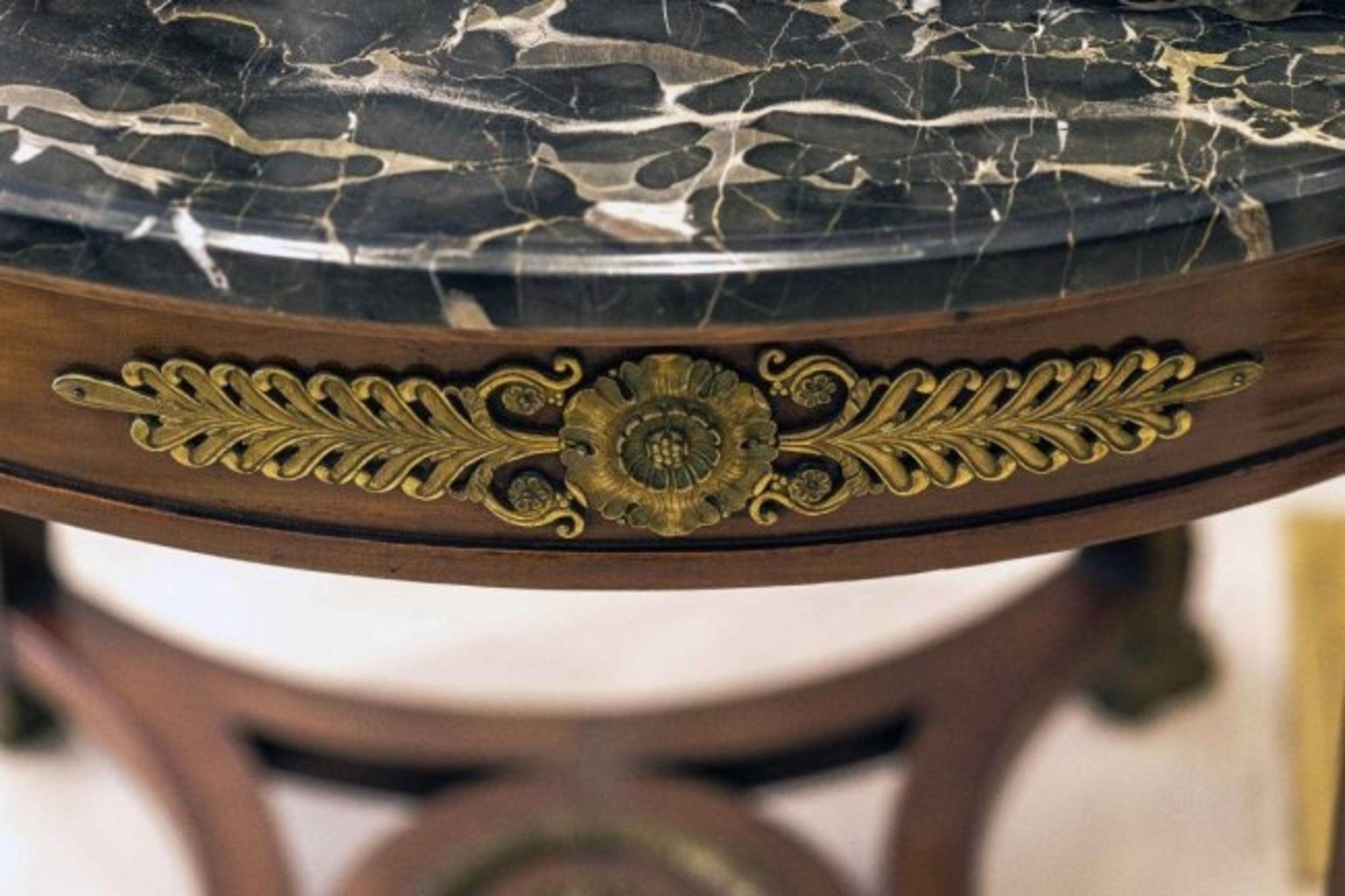 Marble bronze mahogany bouillotte table, circa 1900, the circular tan and white veined black marble top above a decorated frieze on straight supports headed by bronze Egyptian terms and ending in human feet, joined by an interlaced platform