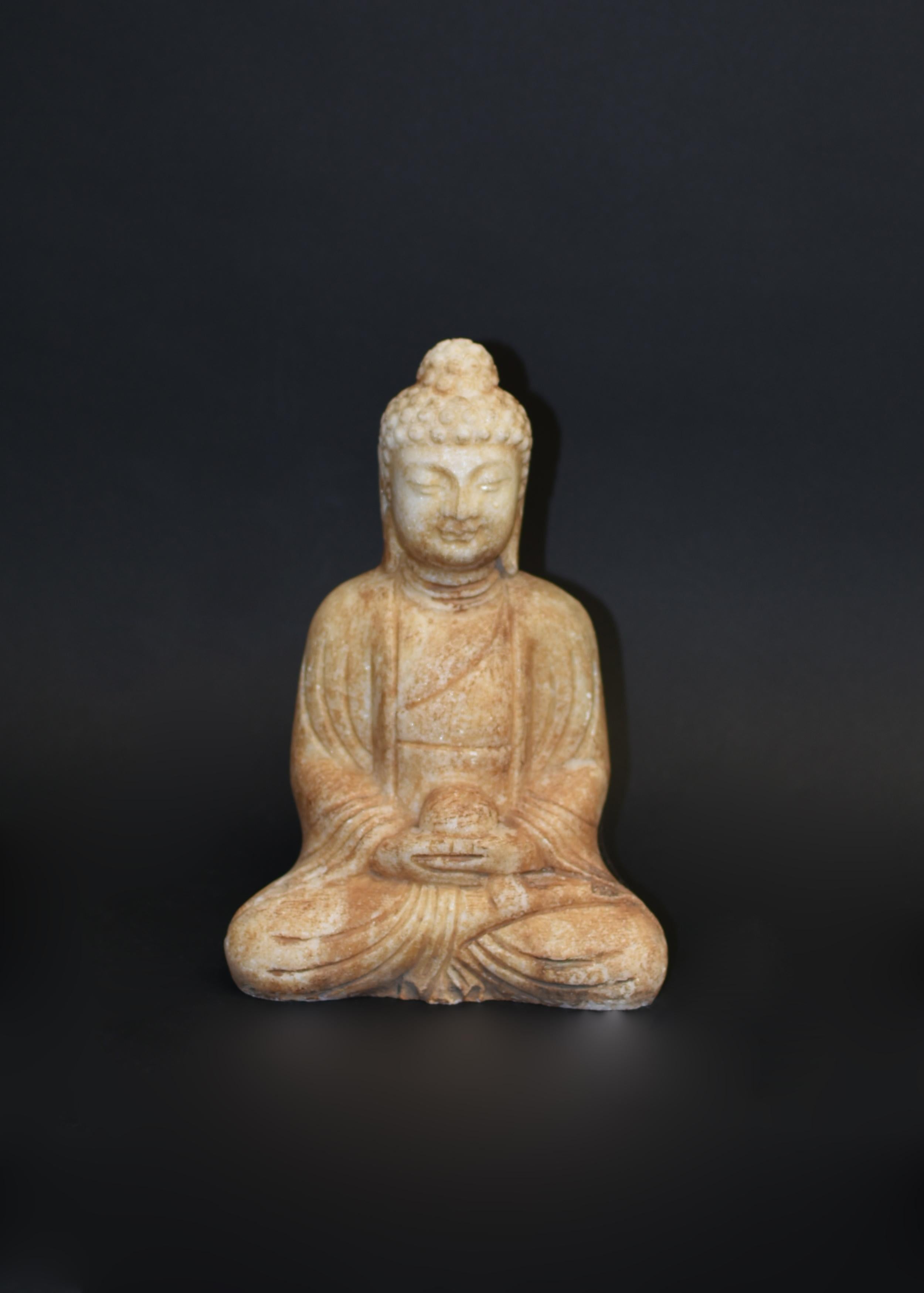 A hand carved 13.3 lb solid marble Buddha statue. Seated dhyana asana with hands in dhyana mudra, Buddha has a beautiful smile with broad face and large downcast eyes, flanked by pendulous earlobes, all under neatly coiled hair which is surmounted