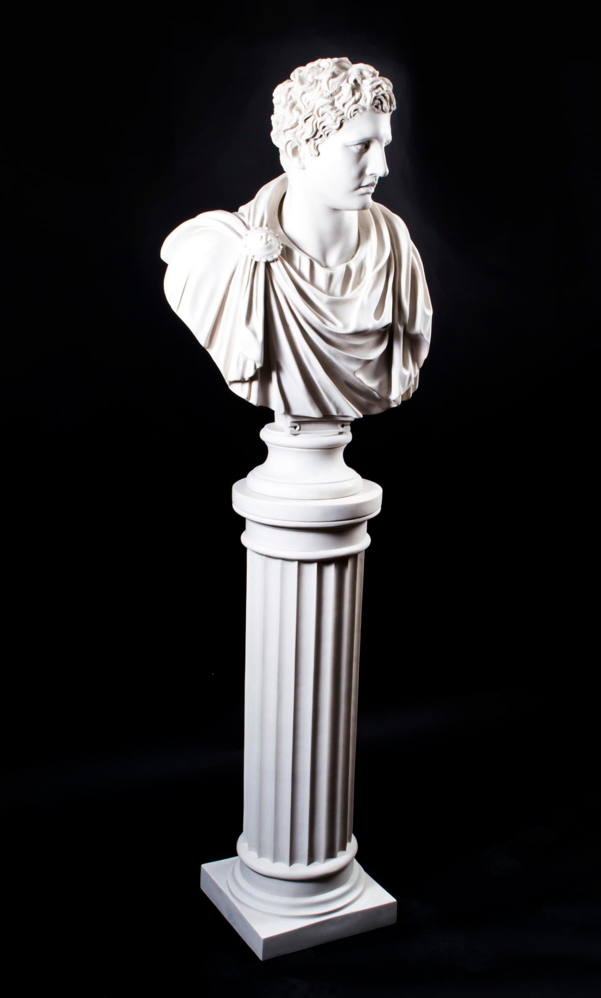 A beautifully sculpted marble bust of the famous Roman general and Emperor Marc Antony, wearing a flowing toga with a fibulae or broach holding it in place, on a matching elegant pedestal in the form of a classical ancient Greek Doric column. The