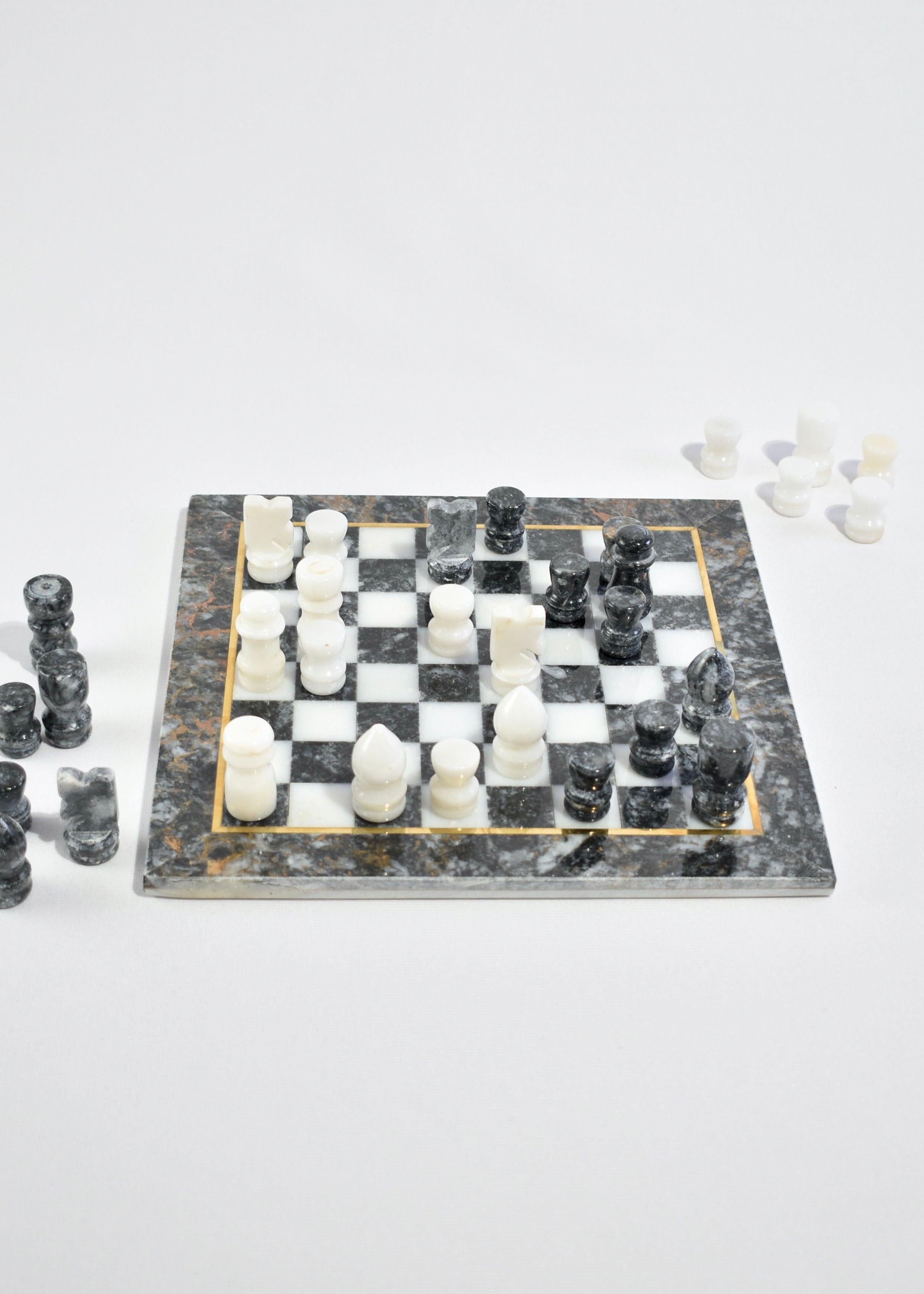 Marble chess board with brass inlay and hand carved pieces in gray and white. Includes 32 chess pieces and board.