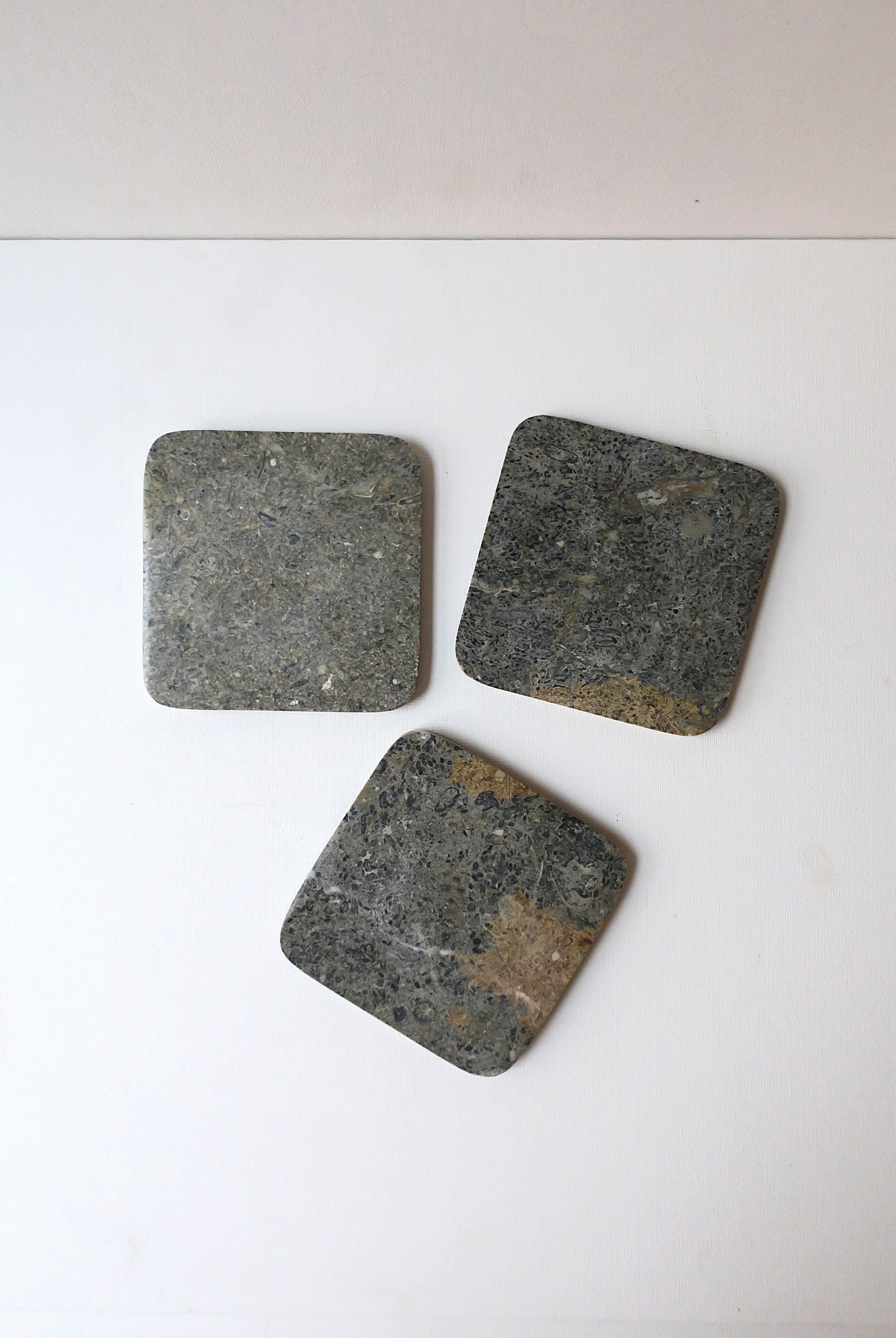 A set of three (3) gray and tan marble drinks coaster, in the Postmodern design style, circa late-20th century. A great set with in grey and tan hues with soft corners and cork bottoms. Perfect for drinks, cocktails, champagne, etc. A great addition