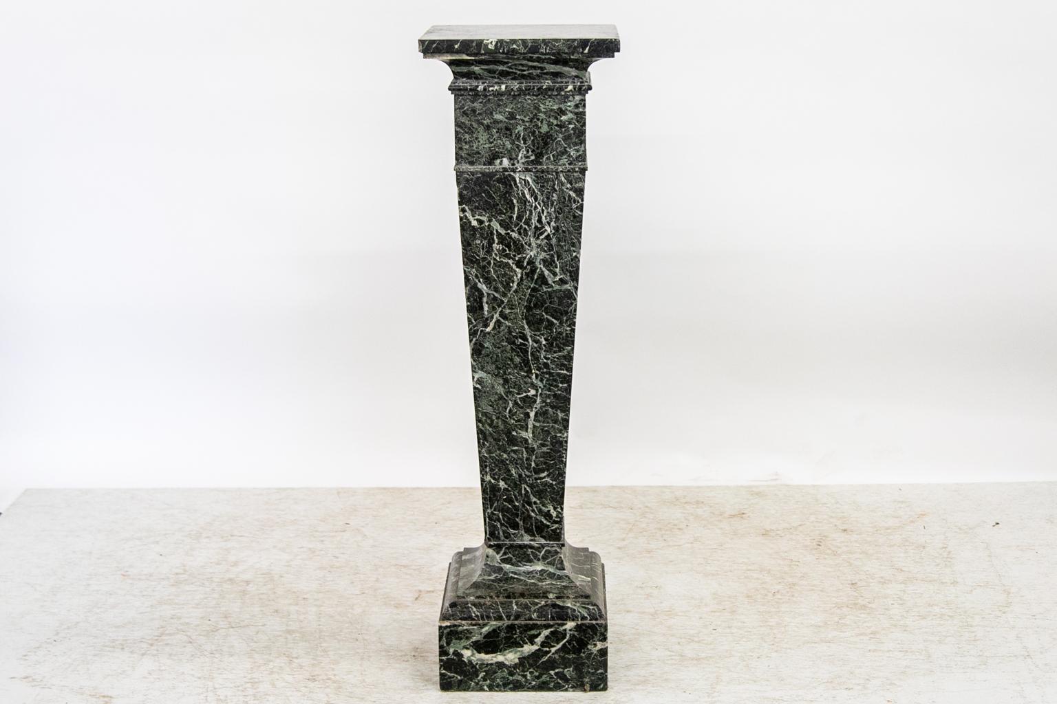 This marble column has carved shapings at the top and bottom. The top has had several repairs. The upper molding has some chips on the edges.