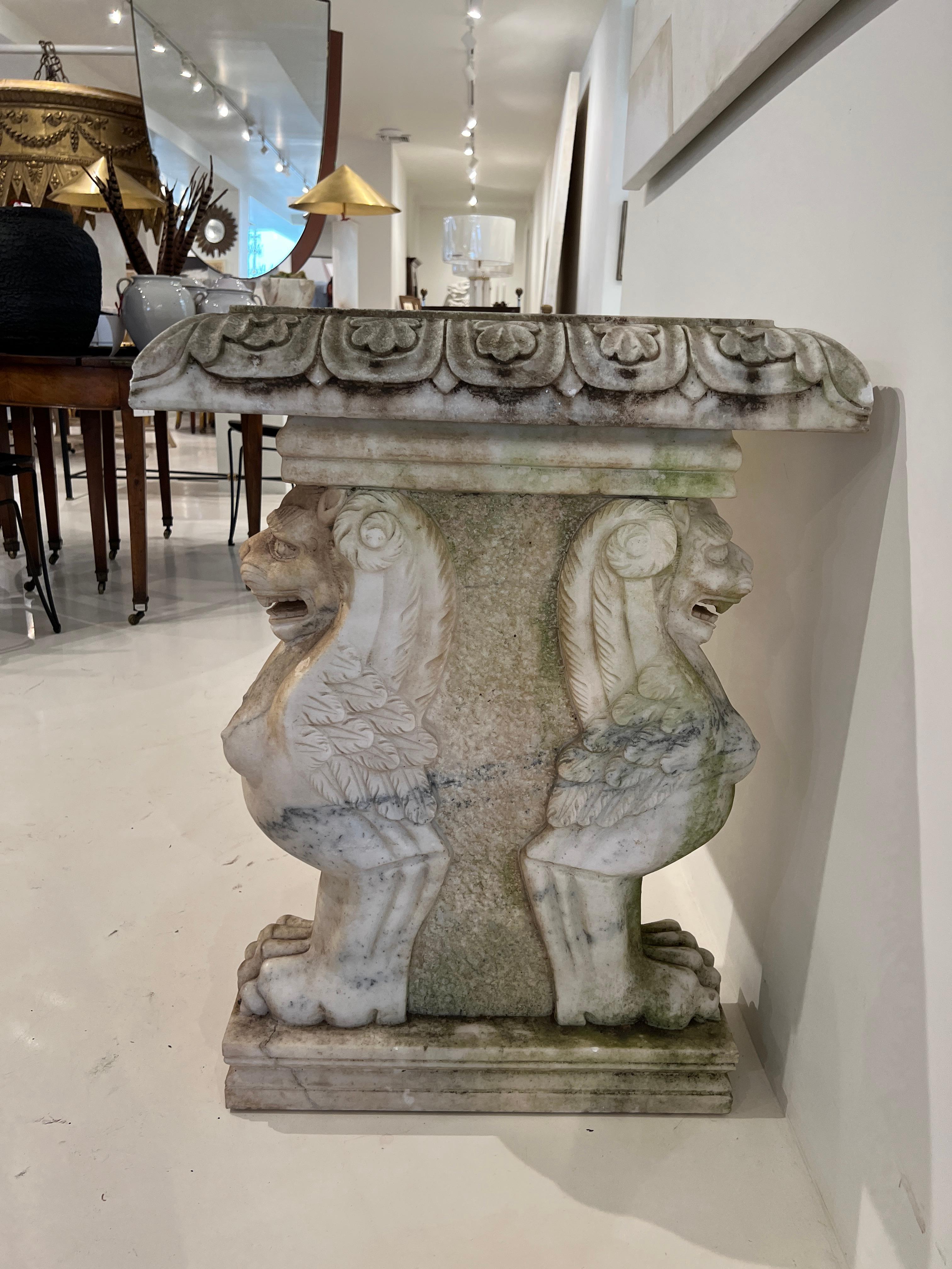A real scene stealer. This magnificent table is solid marble from top to bottom. The base features winged lions with huge claws.. This is repeated on both sides so it can be floated in the room. Some cracks, discoloration and losses in areas.