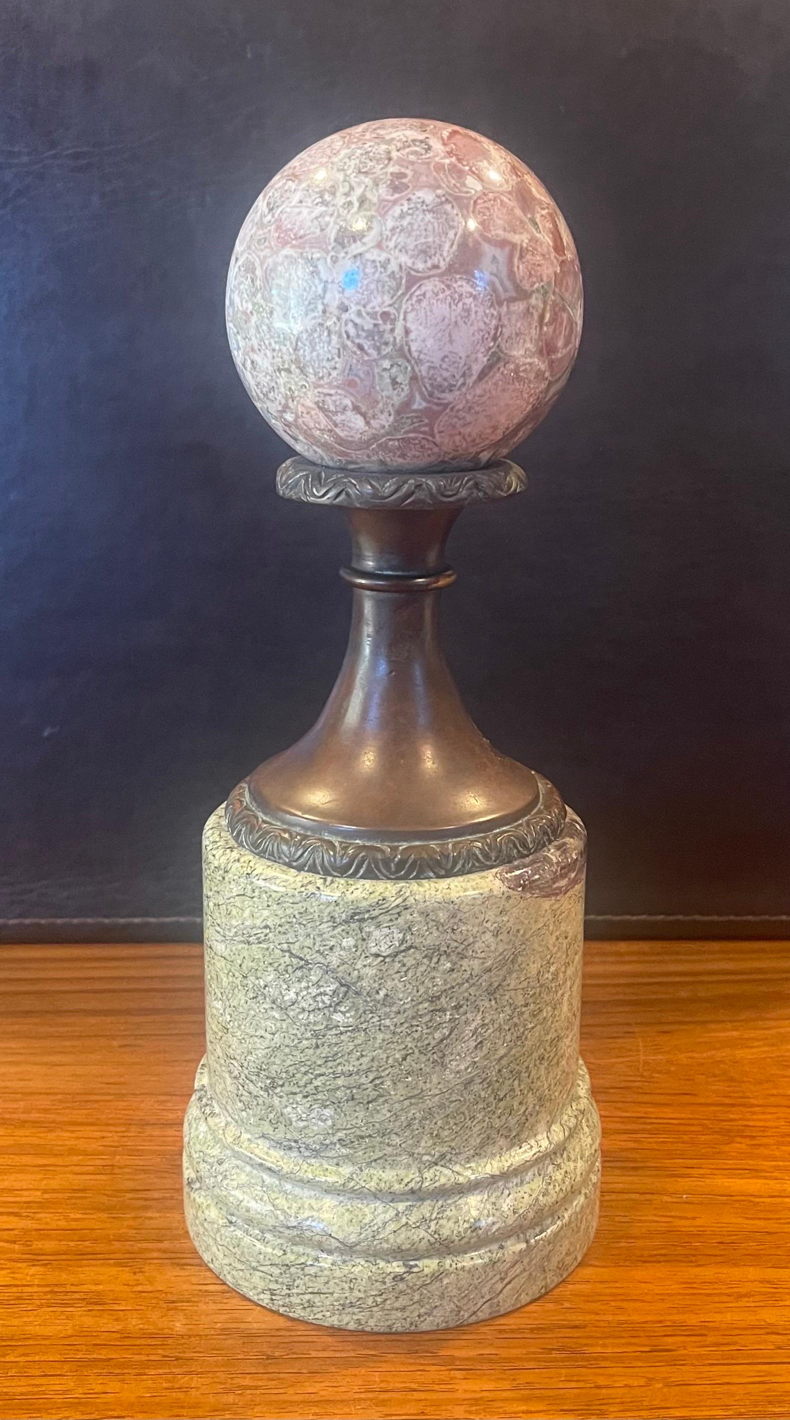 Beautiful decorative marble sphere on bronze and marble base, circa 1990s. The piece is in very good condition with no chips or cracks; it has a nice polished finish with with white, red, grey and green veining and speckles. The sculpture measures