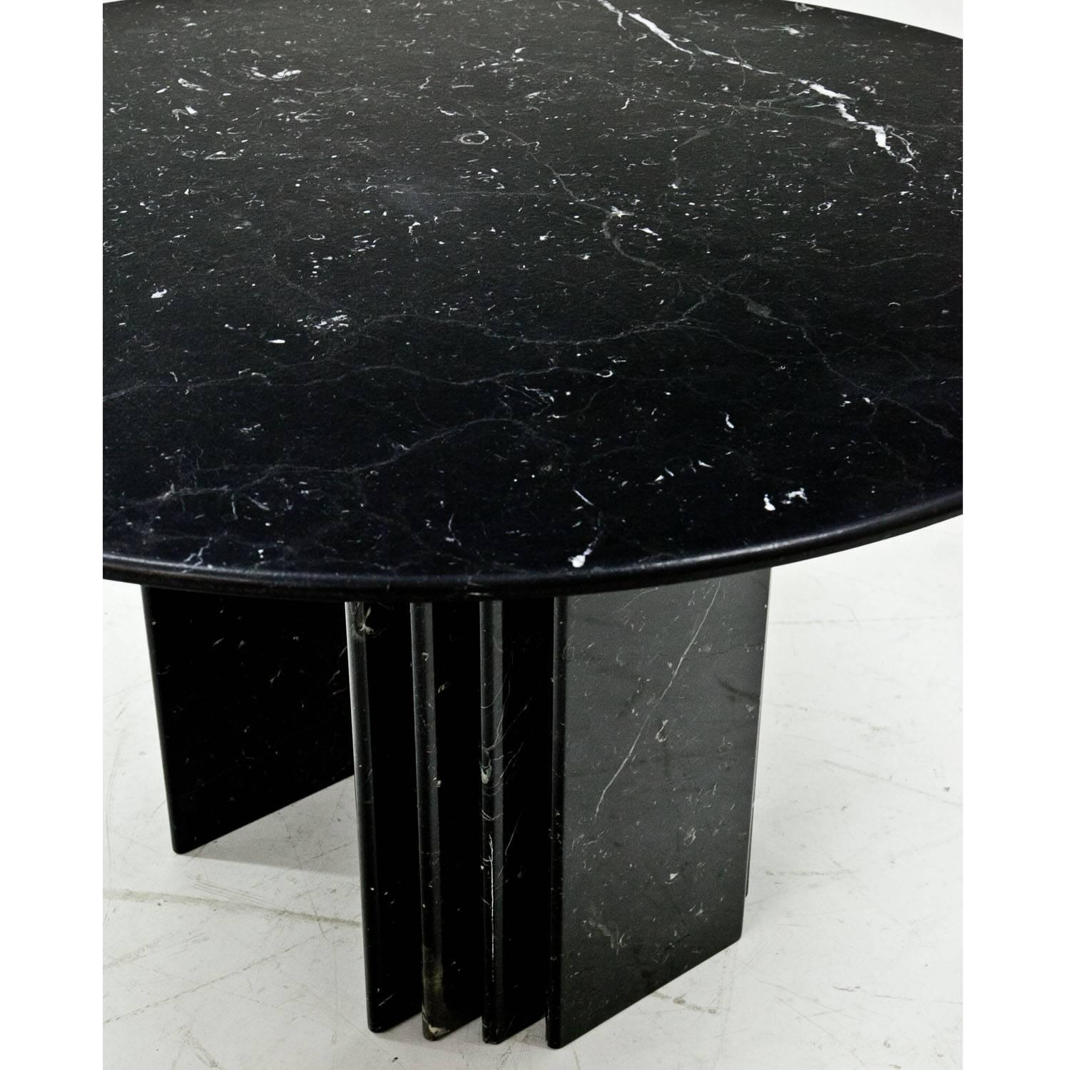 Large dining table out of black marble with white veins. The round tabletop rests on a two-legged marble base. Heavy and stable construction.