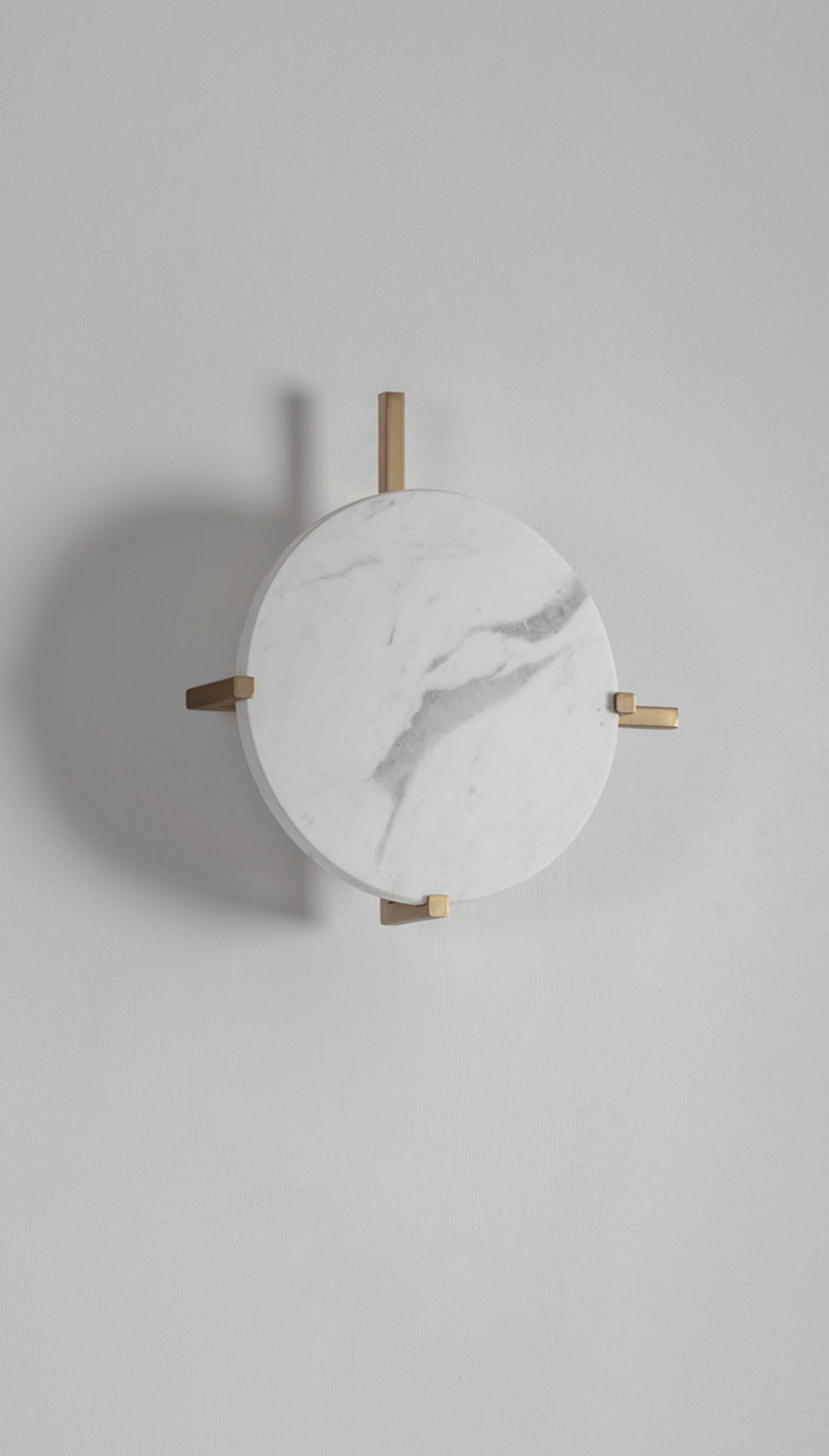 Marble Disc Wall Light by Square in Circle
Dimensions: W 30 x H 30 x D 4 cm
Materials: Brushed brass finish, white marble

This disc-shaped wall light comes with a metal bracket attached behind. The two arms of the bracket project beyond the disc