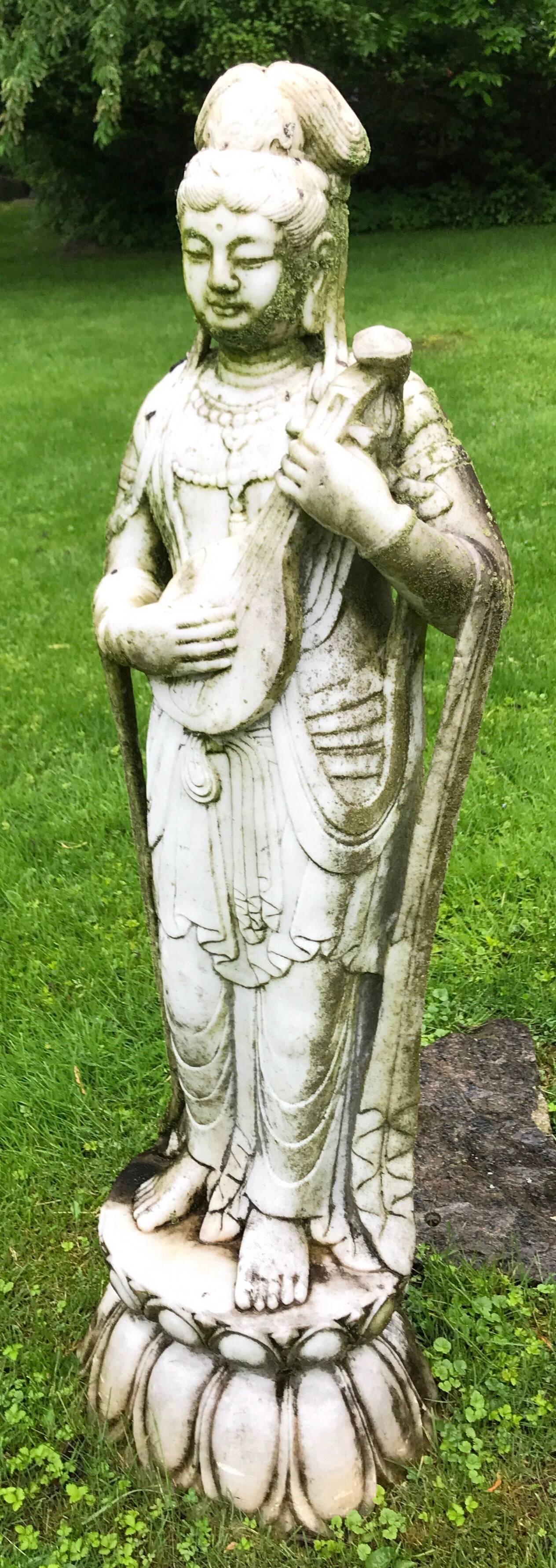 Large marble garden statue of a figure playing a mandolin.