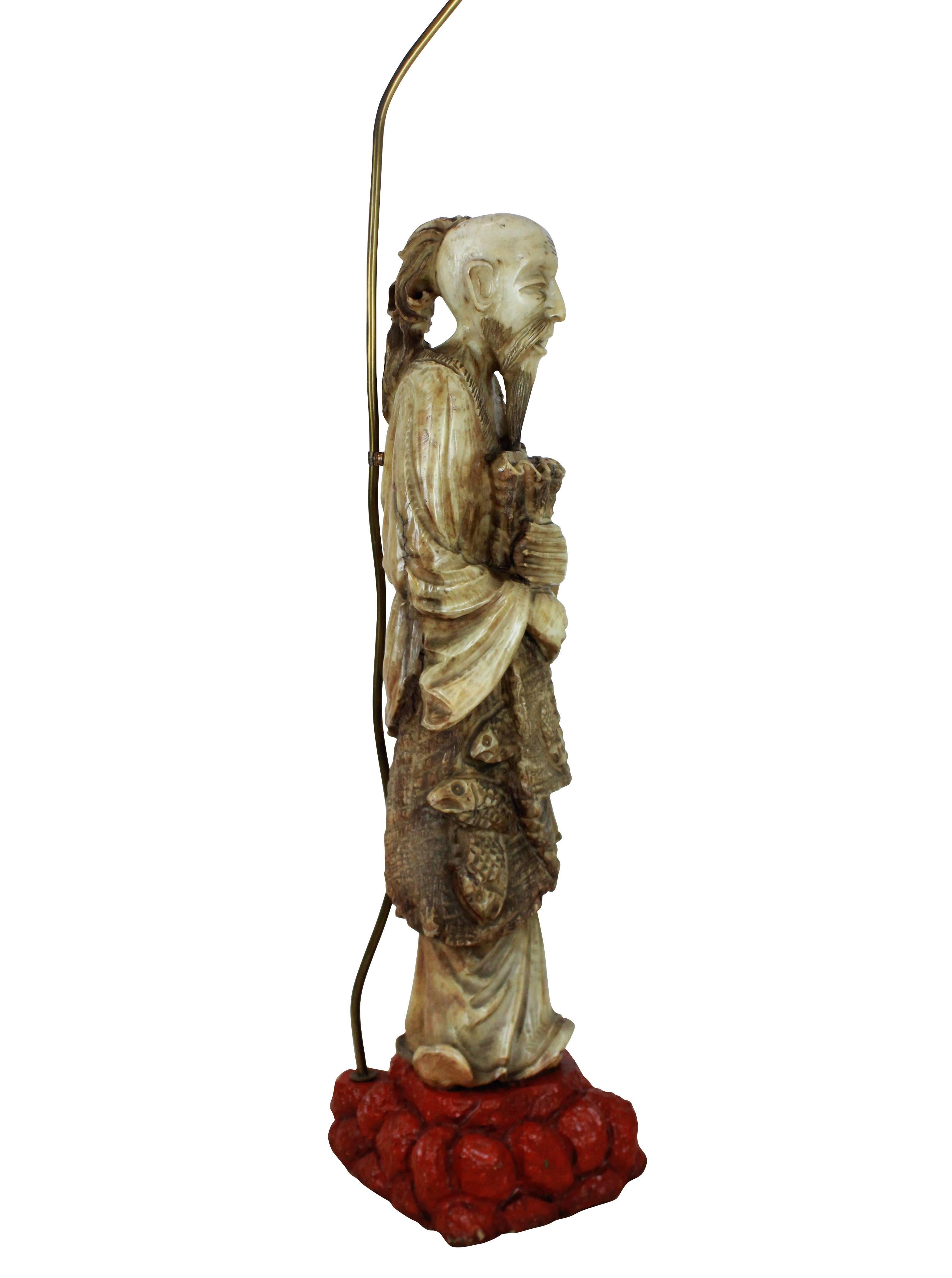 A finely carved Chinese figure of a fisherman, mounted on a red lacquered stone base, converted into a floor lamp.

 The figure is 19th century.
