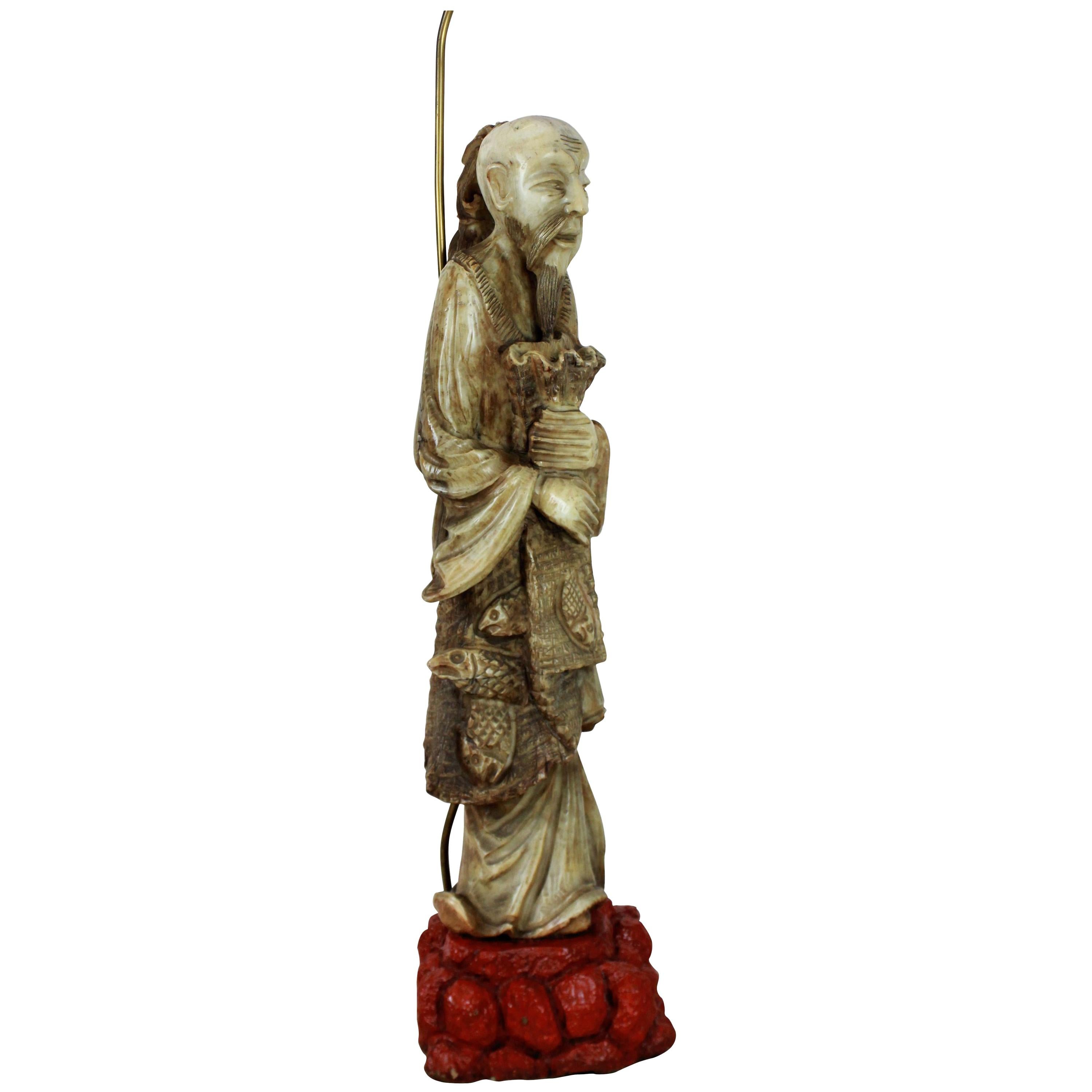 A finely carved Chinese figure of a fisherman, mounted on a red lacquered stone base, converted into a floor lamp.

 The figure is 19th century.