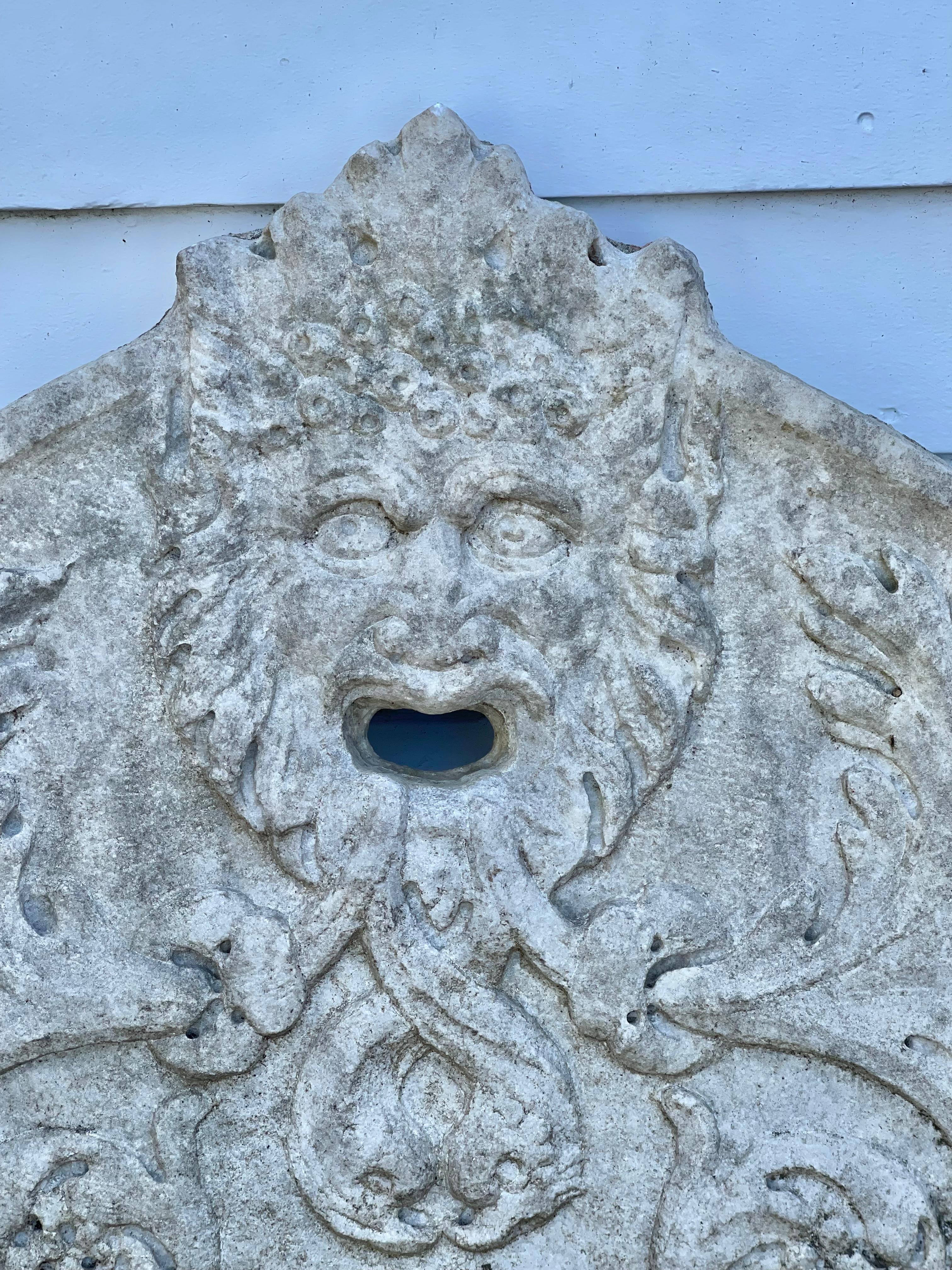 Carved marble fountain plaque with Italian archaic face.

Provenance: By Repute, Astor's Ferncliff, Rhinebeck, New York.
