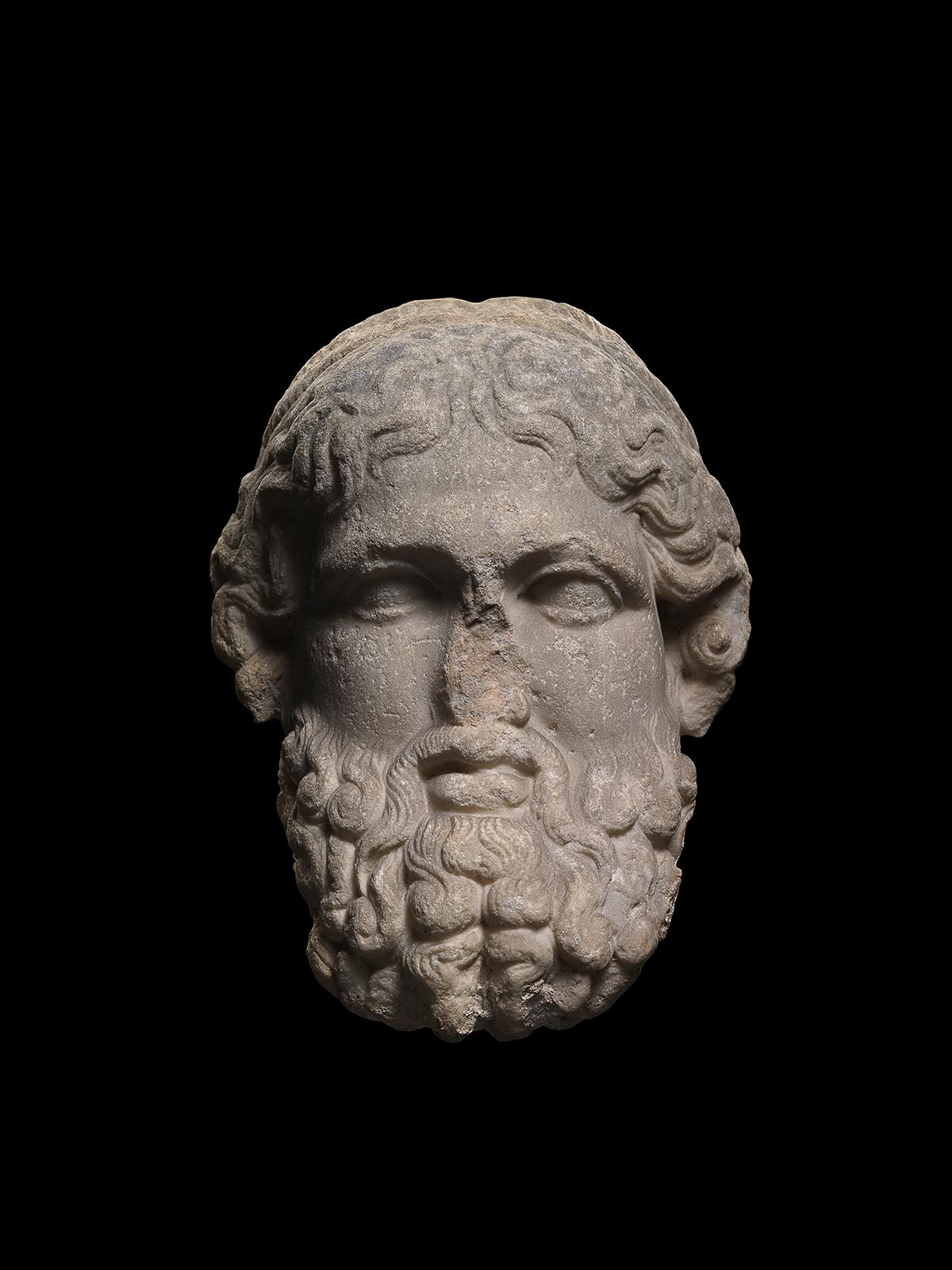 Römischer Kopf des Gottes Hermes in archaisierendem Stil, nach einem griechischen Vorbild aus dem vierten Jahrhundert v. Chr. Hermes ist in der für Hermen typischen Weise dargestellt, mit einem Vollbart aus langen gelockten Locken, einem dicken