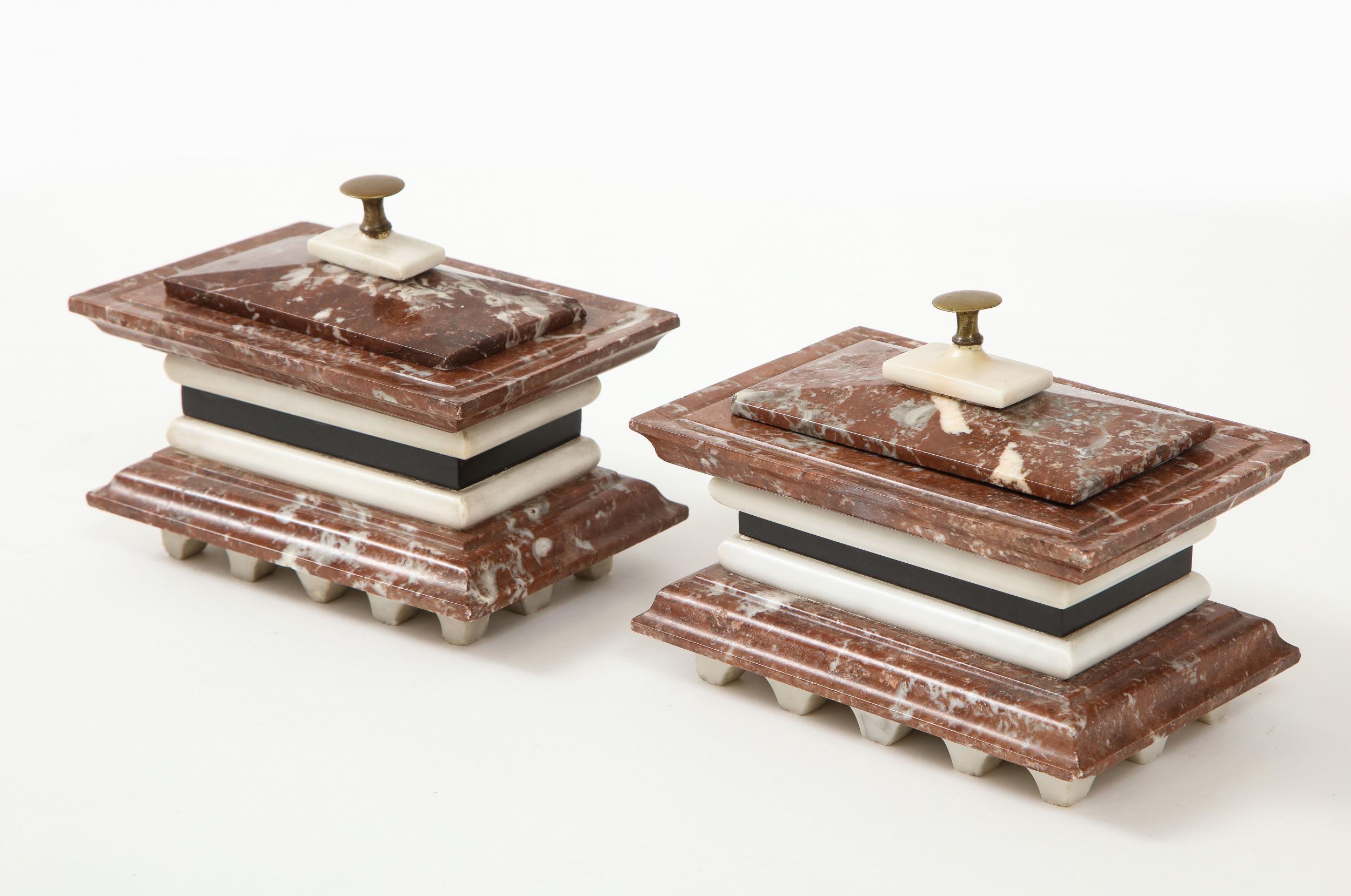 A pair of Italian marble ink wells with covered well and brass handle. Beautiful contrasting black, white, and red marbles make up the body and lid of this pair. White late 19th century, circa 1890.