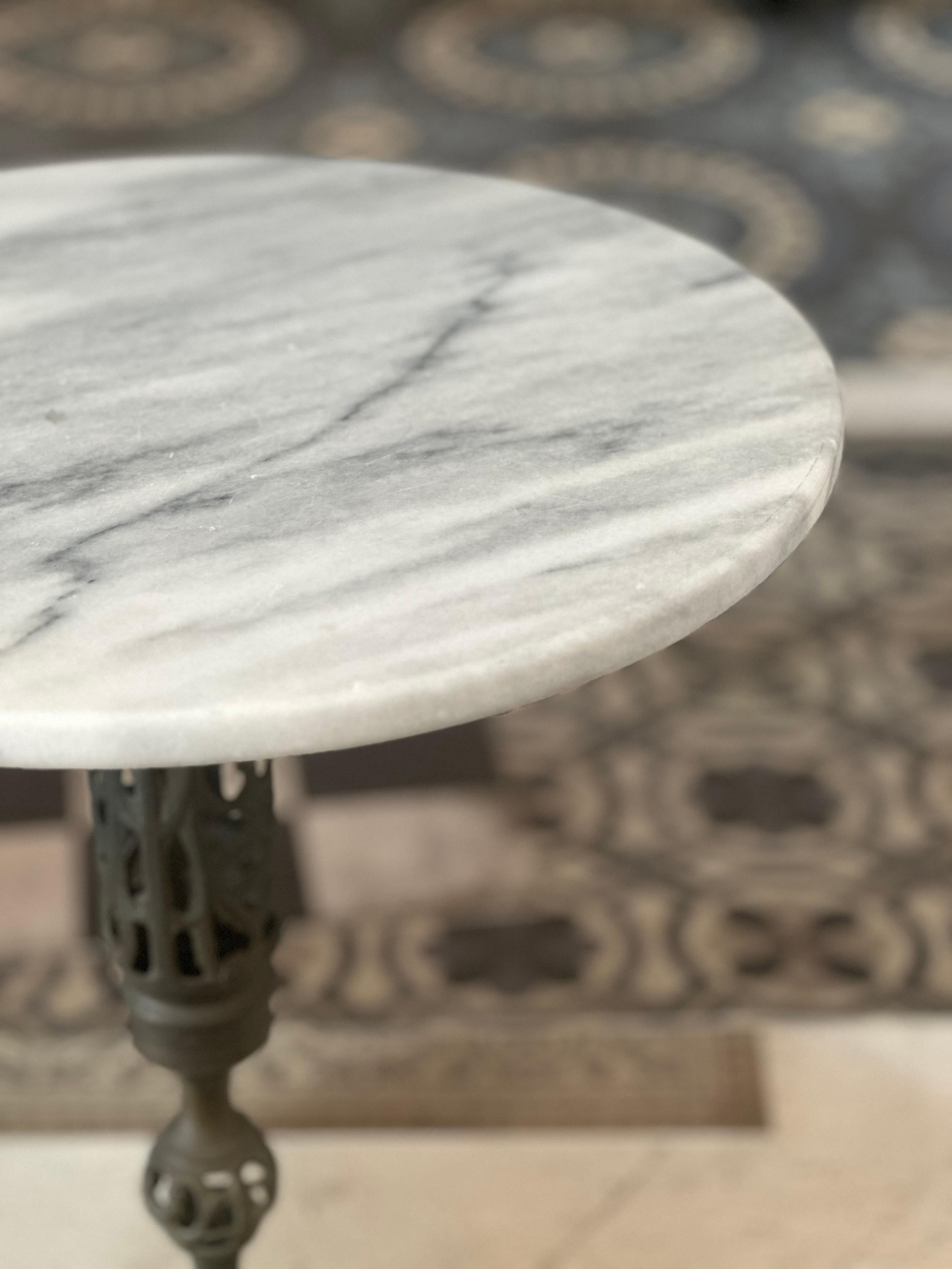 This vintage marble and iron side table brings an elegant touch to any space. It features a beautifully veined round marble top paired with an ornate cast iron base, showcasing intricate openwork details. A perfect accent piece for both classic and