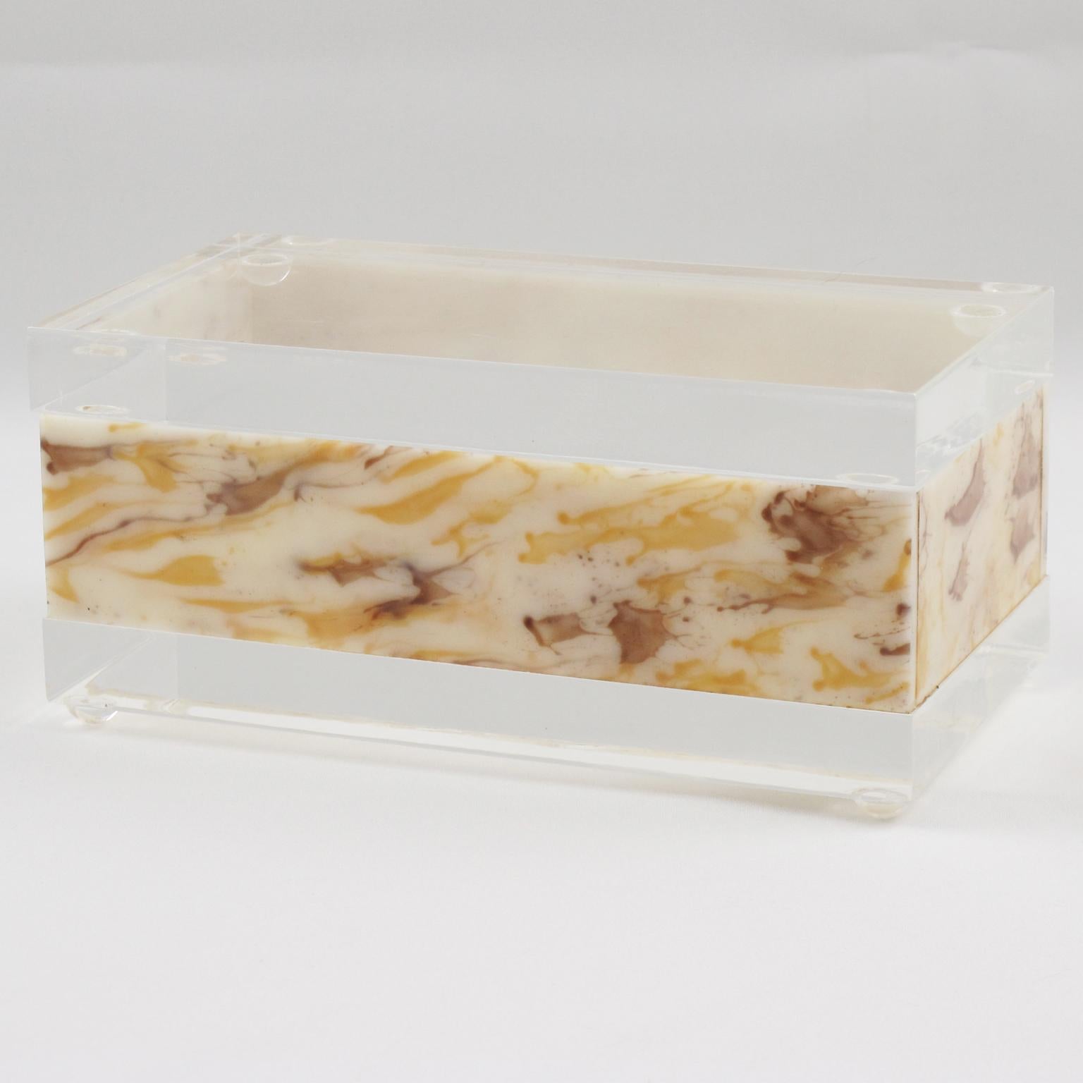 Esta impresionante caja modernista de Lucite se fabricó en la década de 1970. Su forma rectangular ostenta un diseño de Lucite o acrílico cristalino y textura de imitación de mármol. El luminoso color miel lechosa y ámbar arremolinado parece mármol