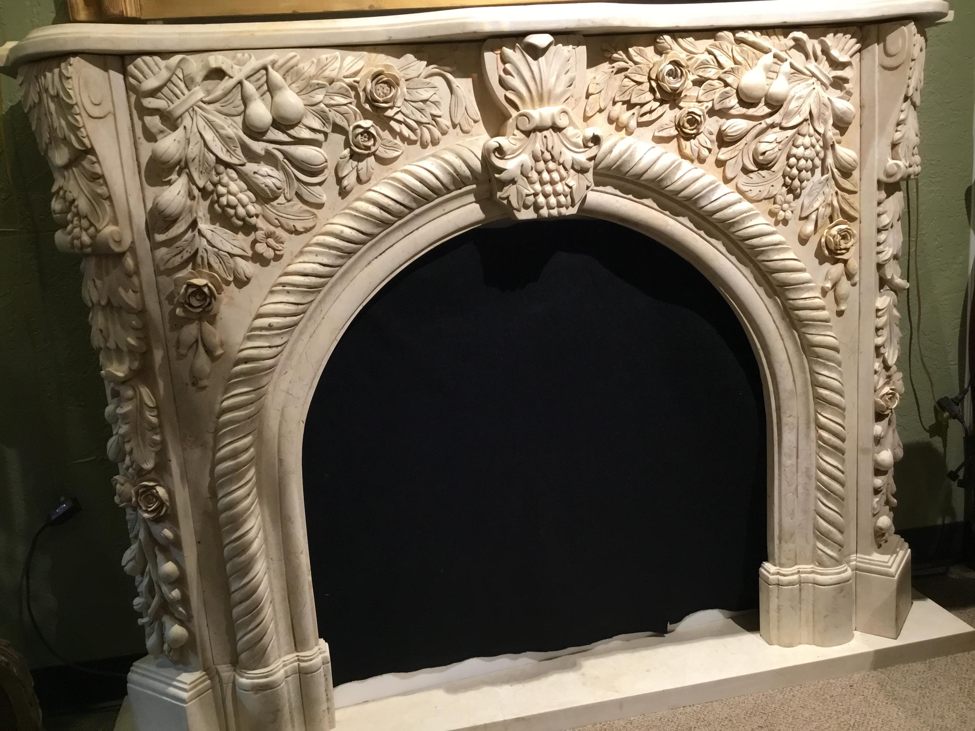 Marble mantel that has a graceful arch center and has been hand carved
with foliate design and fruit and flowers. A roped edge follows the arch.
Carved corners add beauty to this handsome mantel.