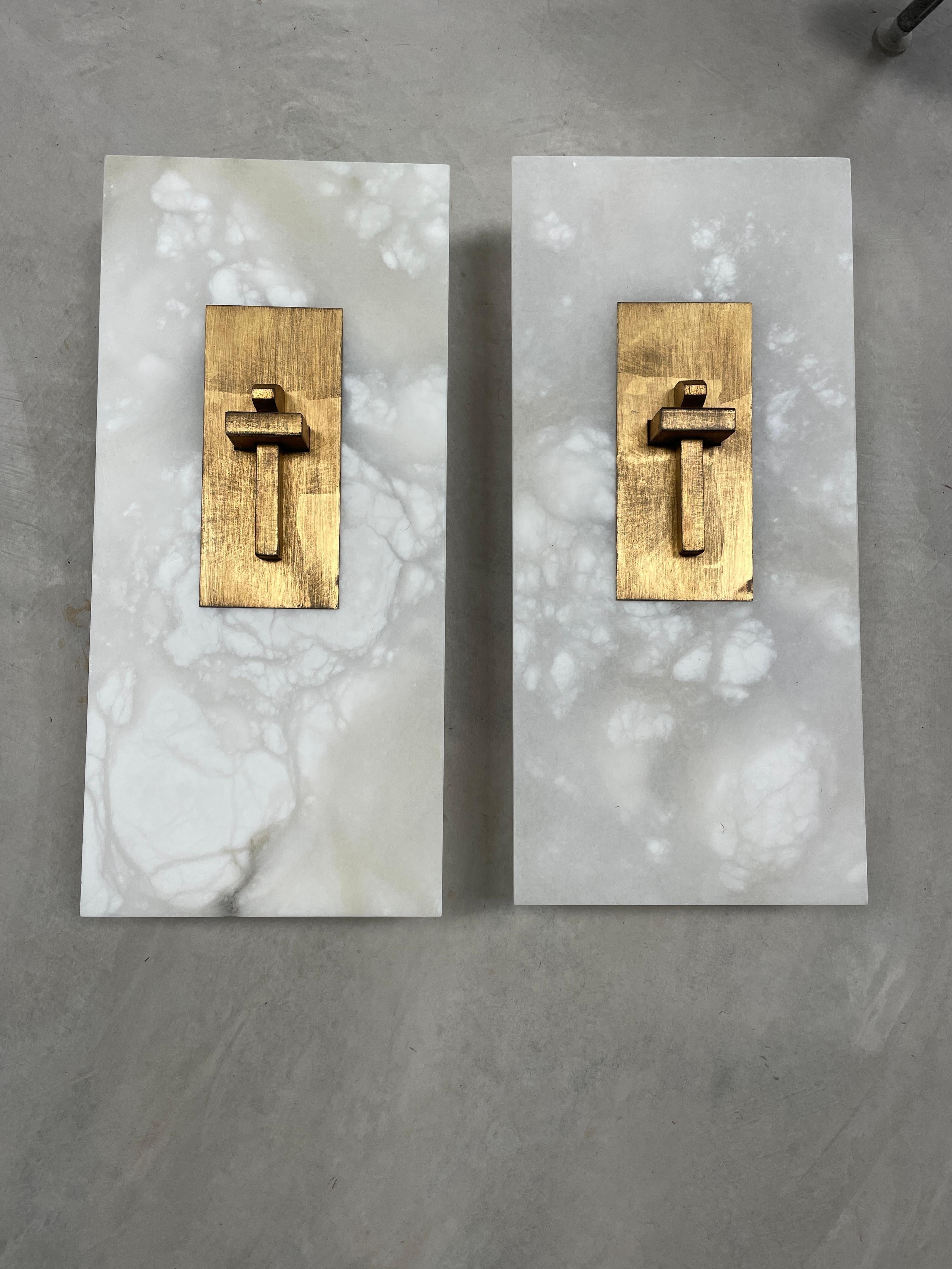 Add a touch of elegance to your home decor with this stunning pair of marble and metal wall sconces. The contemporary design features a rectangular shape, hardwired power source, and a light sensor type. The sconces are made with high-quality metal