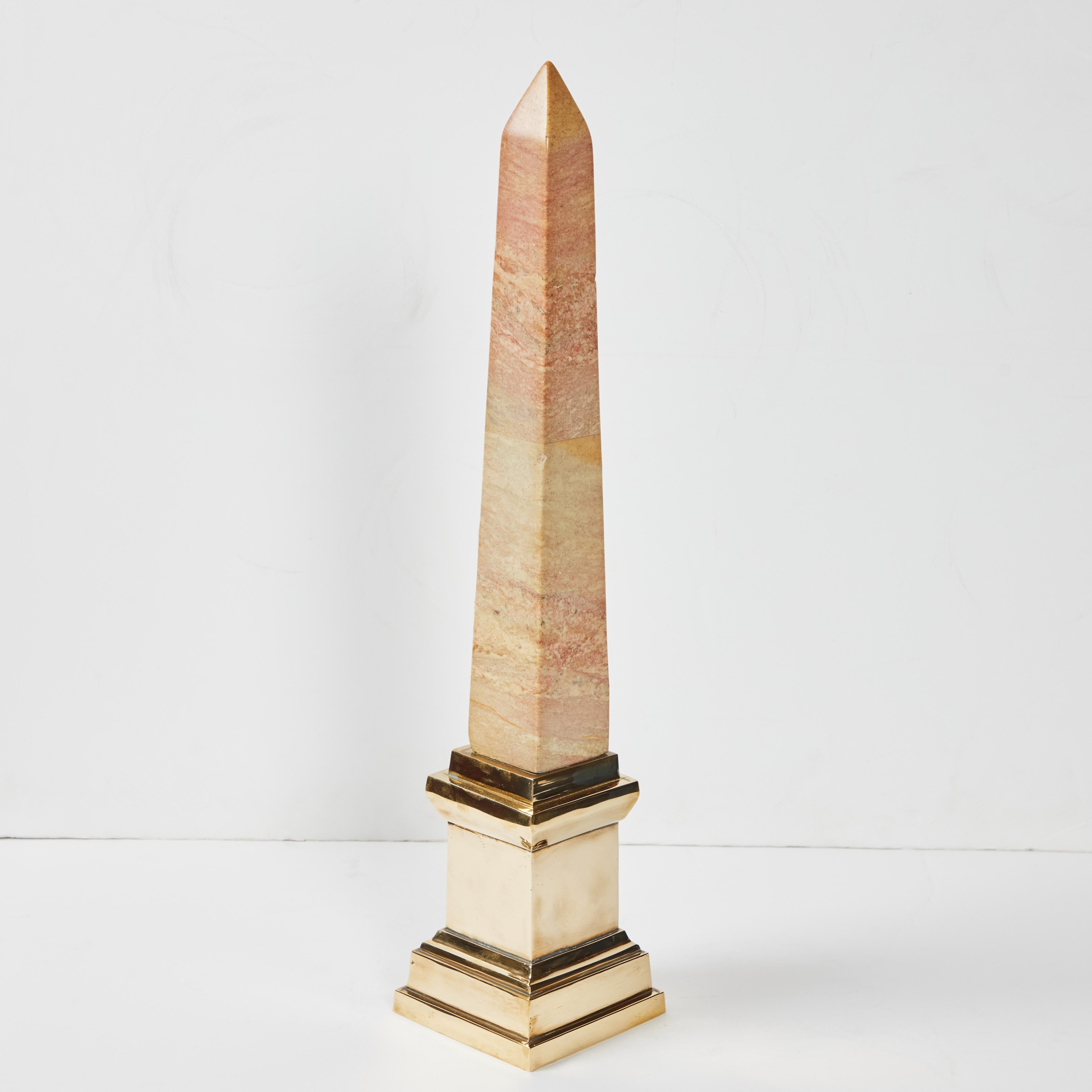 A hand carved and polished marble obelisk in pastel tones on a polished brass base.  
