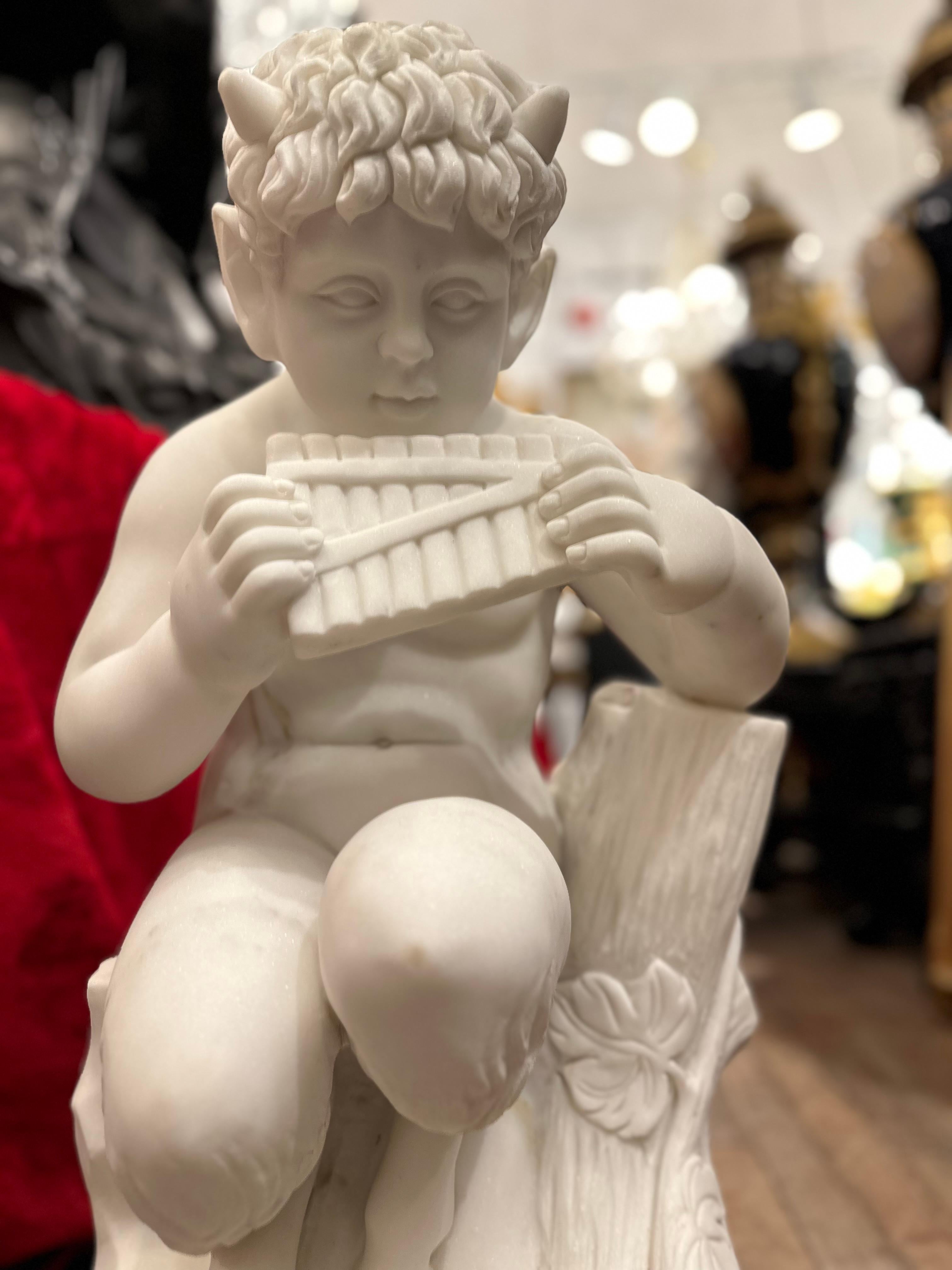 Beautifully and carefully carved Marble Statue of Pan playing a flute. The features are clearly visible and well done, with Pan pursing his lips to blow into the flute. A lovely realistic portrayal of Pan which even includes the dimples on his lower
