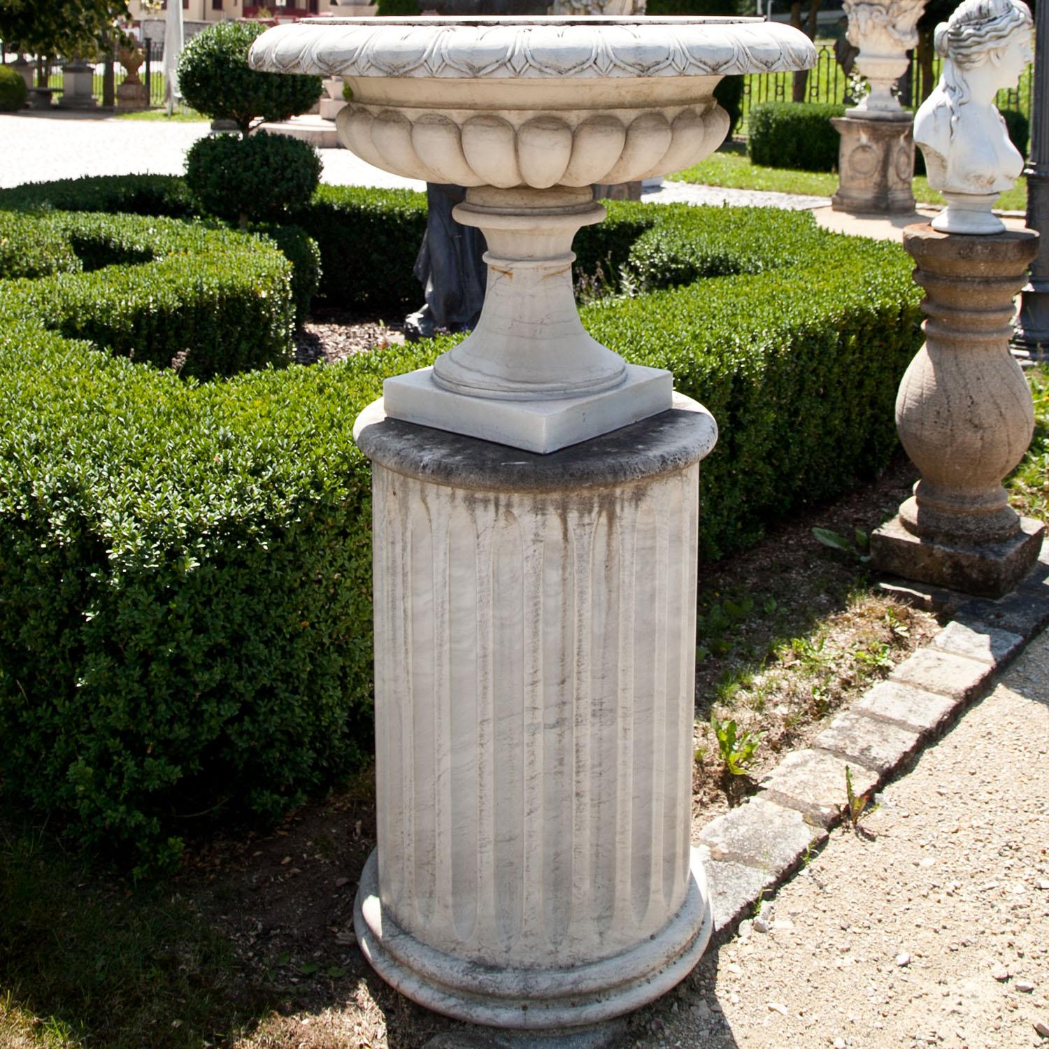 Planter out of white marble, standing on a square plinth with a conical foot and a large dish with gadrooned wall and cymatium frieze on the rim.