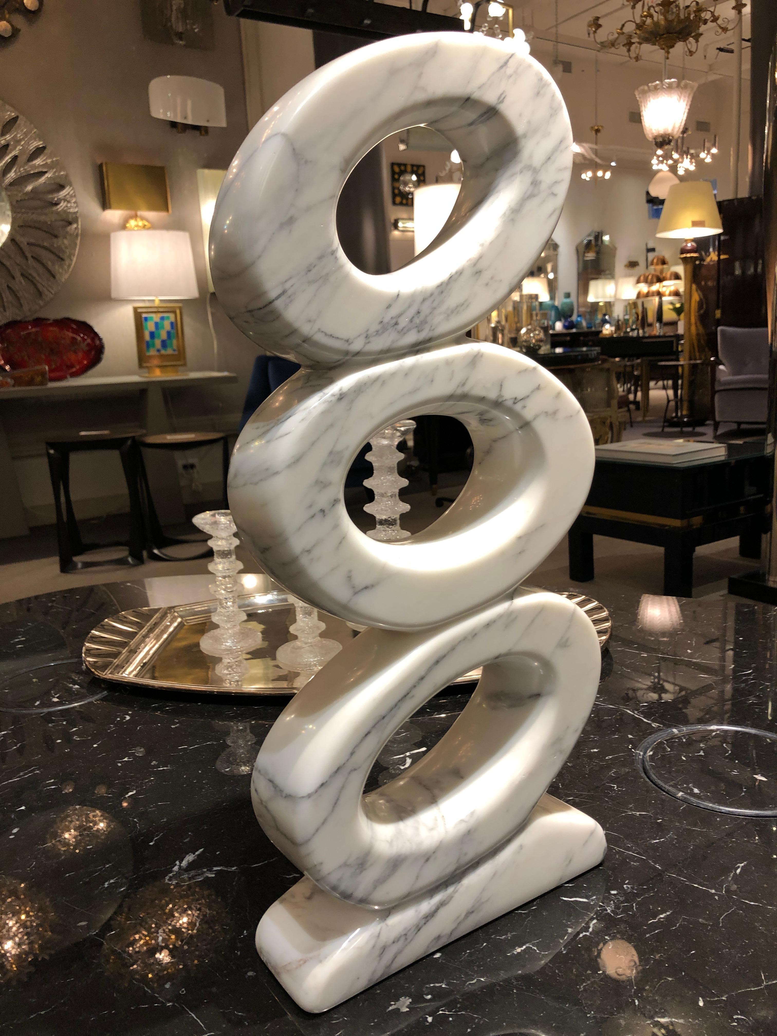 The sculpture is formed of three abstract intertwined loops in white marble with light gray veining throughout. Signed at the base.