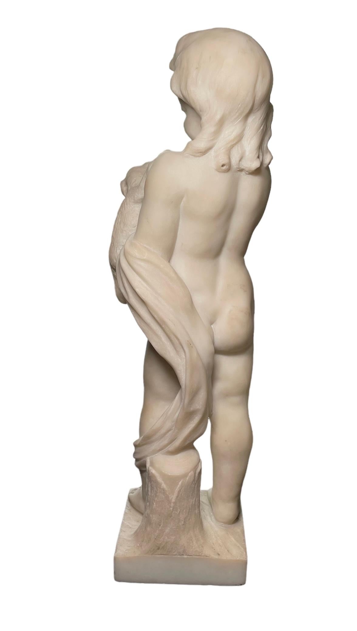 This is a marble sculpture of a cherub who is standing up in front of a trunk. His head has an abundant hair with curly ends. He is gently holding a puppy. The sculpture has attached a square alabaster base.