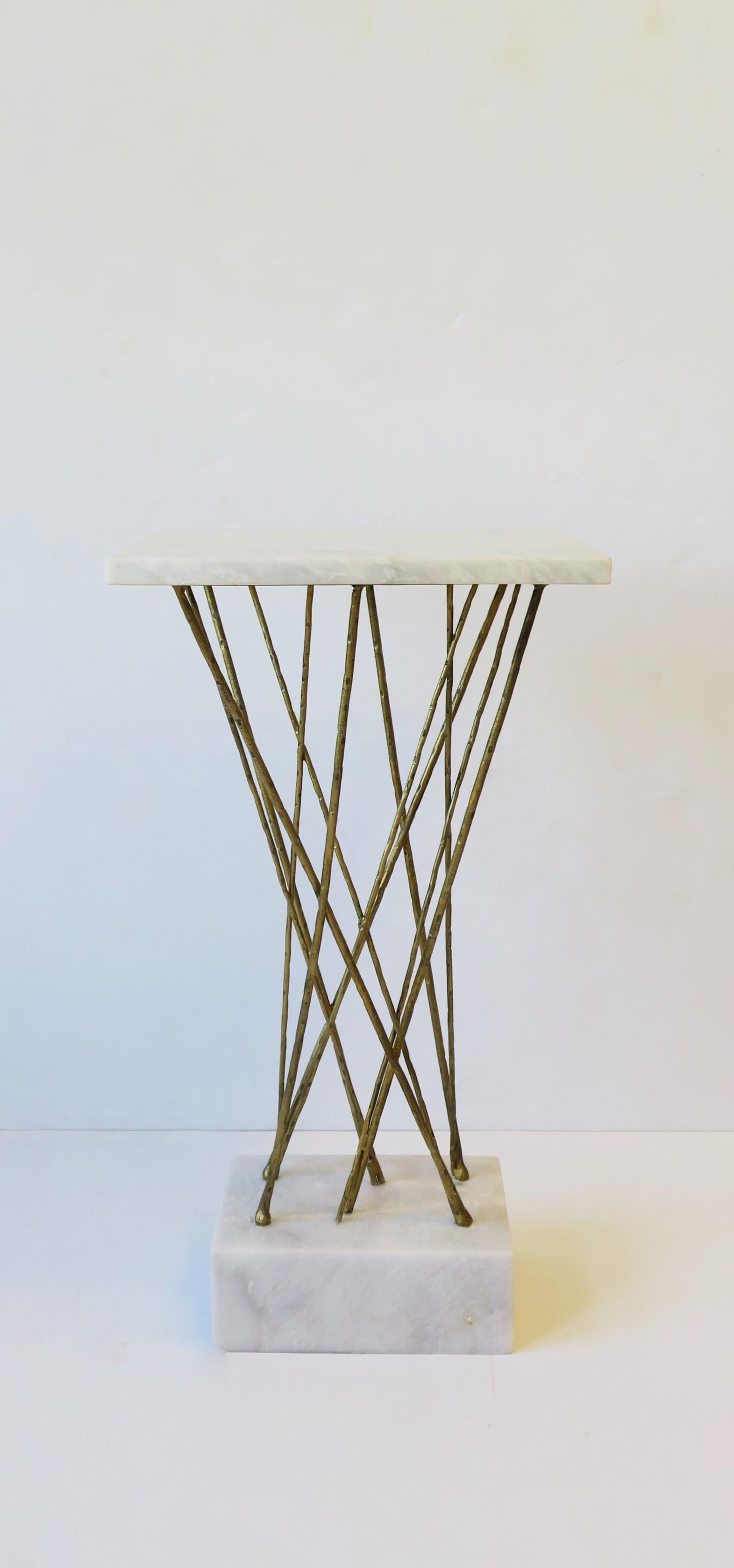 A substantial marble side or drinks pedestal table with a brass colored gold-tone metal geometric center. Table has a rectangular marble top, geometric gold-tone metal center, finished with a substantial marble base (base is 3