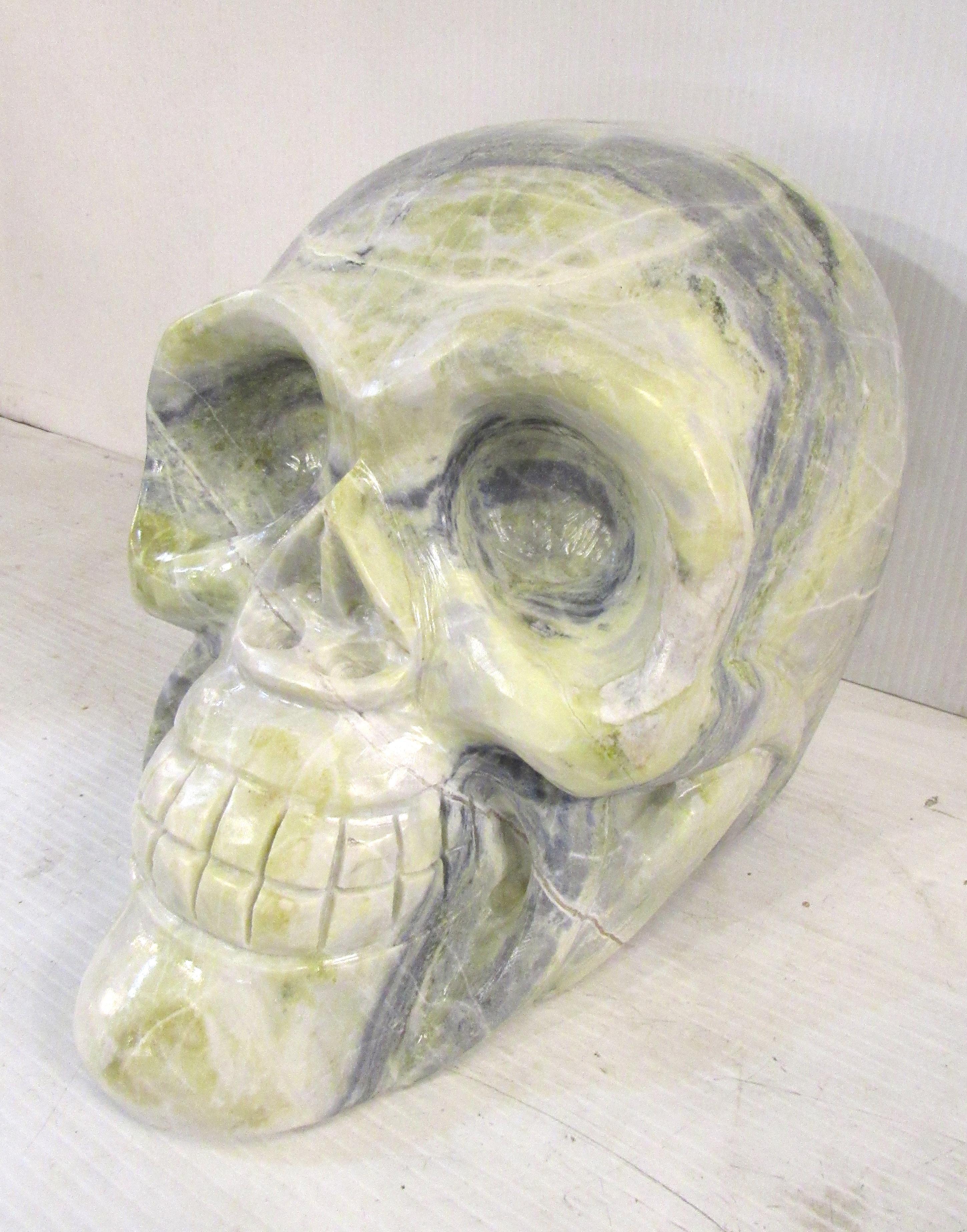 This stylized marble skull is sculpted from solid marble, showcasing the beautiful veins of color throughout the skull. An odd and unusual sculpture, this skull is sure to add a touch of edgy decorative flair to any space. Please confirm the item