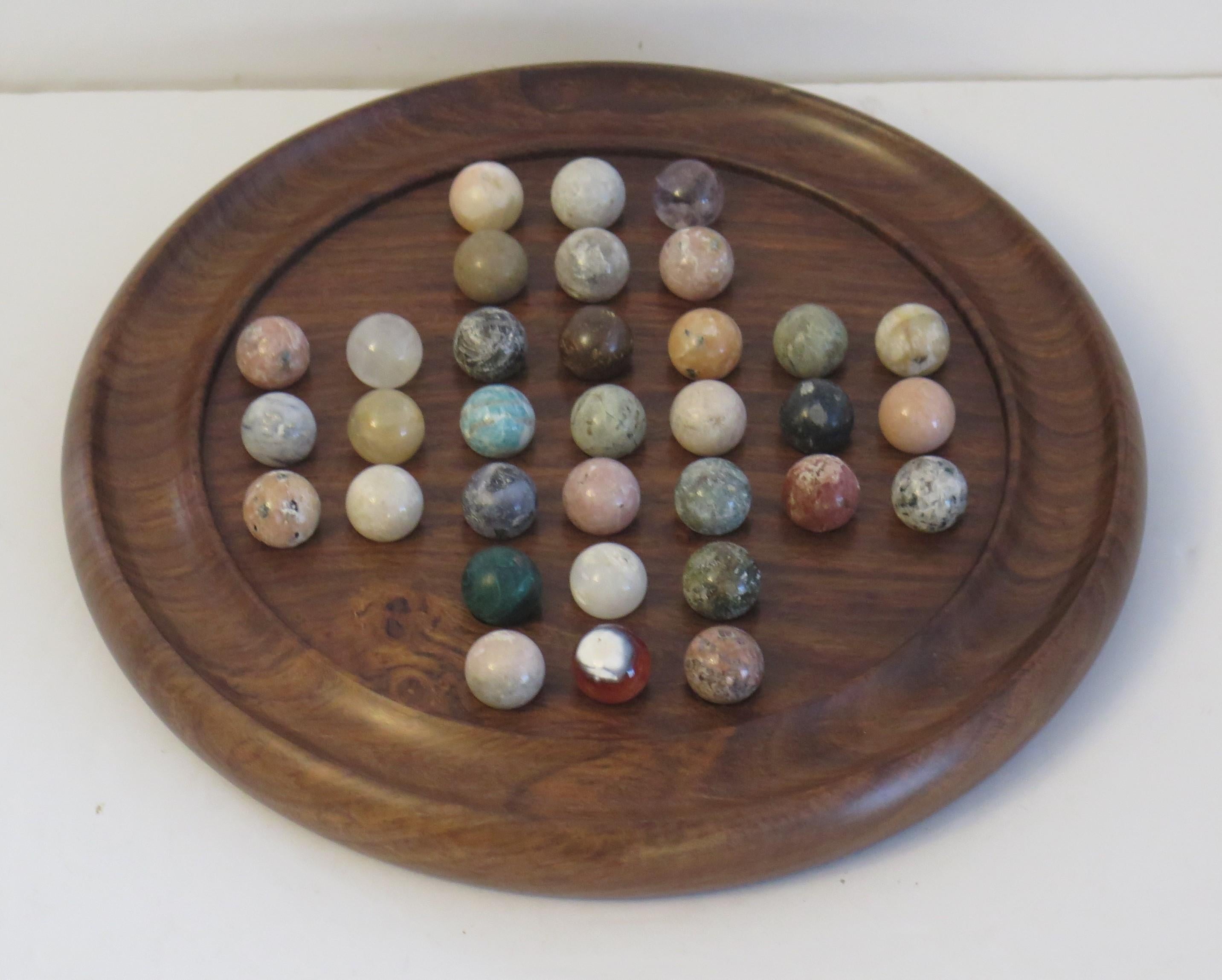 This is a very attractive complete game of Marble Solitaire with a hand turned hardwood board and 33 beautiful agate mineral stone marbles, probably French and all dating to the first half of the 20th century, circa 1930s.

The circular hand