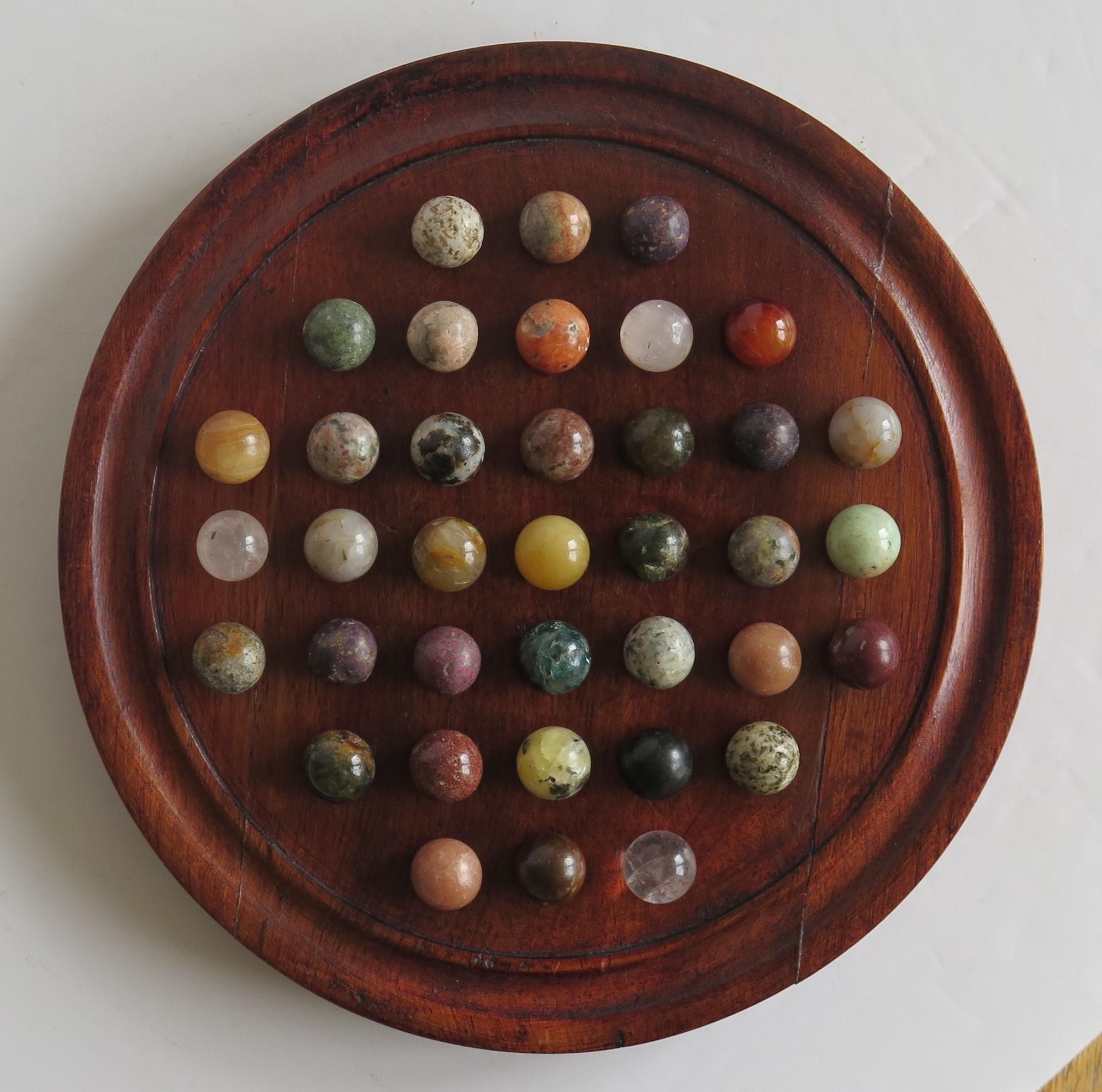 This is a complete game of 37 hole marble solitaire with a good hardwood board and 37 beautiful individual agate marbles, which we date to the early 20th century.

The circular turned board is made of Hardwood with a gallery to the outer rim and