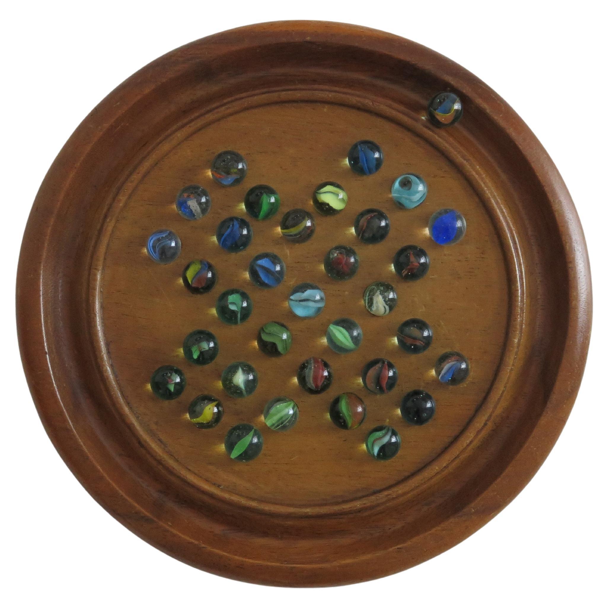Se trata de un buen juego de solitario de canicas, con un tablero de madera dura en muy buen estado y un juego completo de 34 canicas de remolino de cristal, todas ellas de la primera mitad del siglo XX.

La tabla circular torneada a mano es de