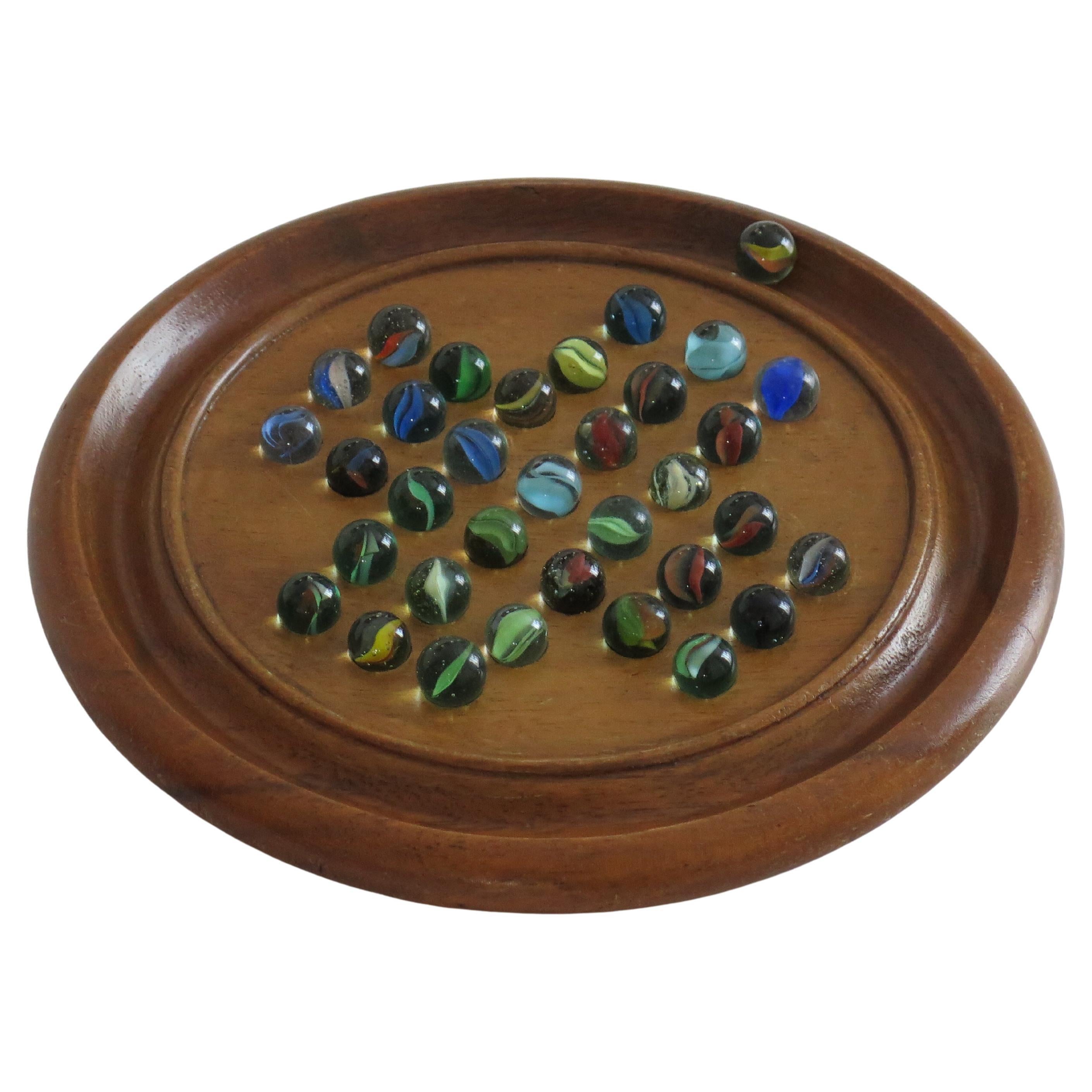 Juego de solitario de canicas Tablero de madera dura con 34 canicas antiguas de cristal arremolinado, Circa 1930 en venta