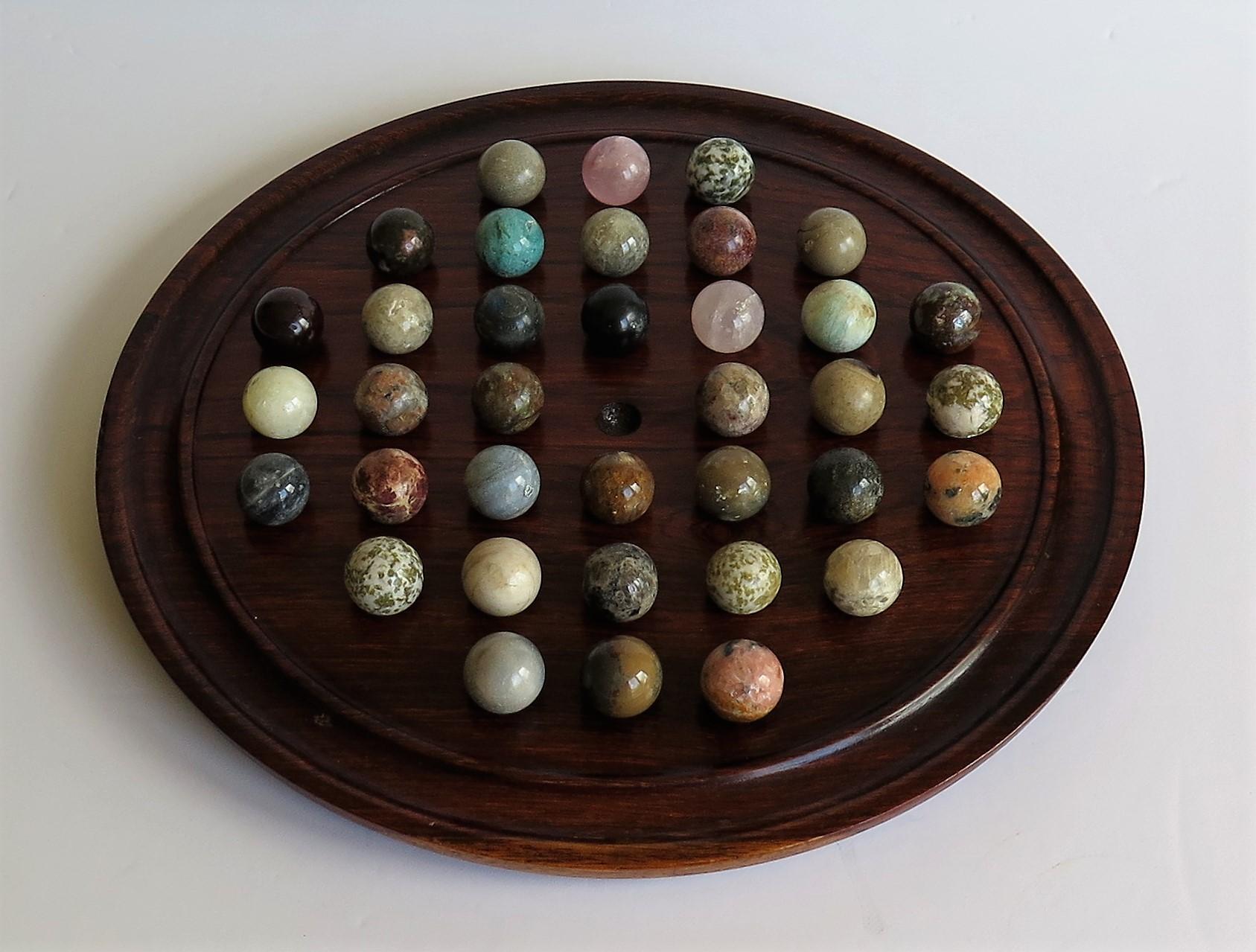 This is a complete Game of 37 hole Marble Solitaire with a polished hardwood board and 36 beautiful individual agate marbles, which we date to the early 20th century.

The circular turned board is made of Hardwood with a gallery to the outer rim.