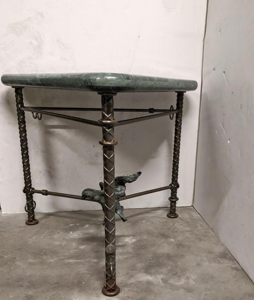 Three legged center table in steel, signed Ilana Goor, has a bronze bird on one of the three stretchers and a triangular top in green marble with rounded edges. 