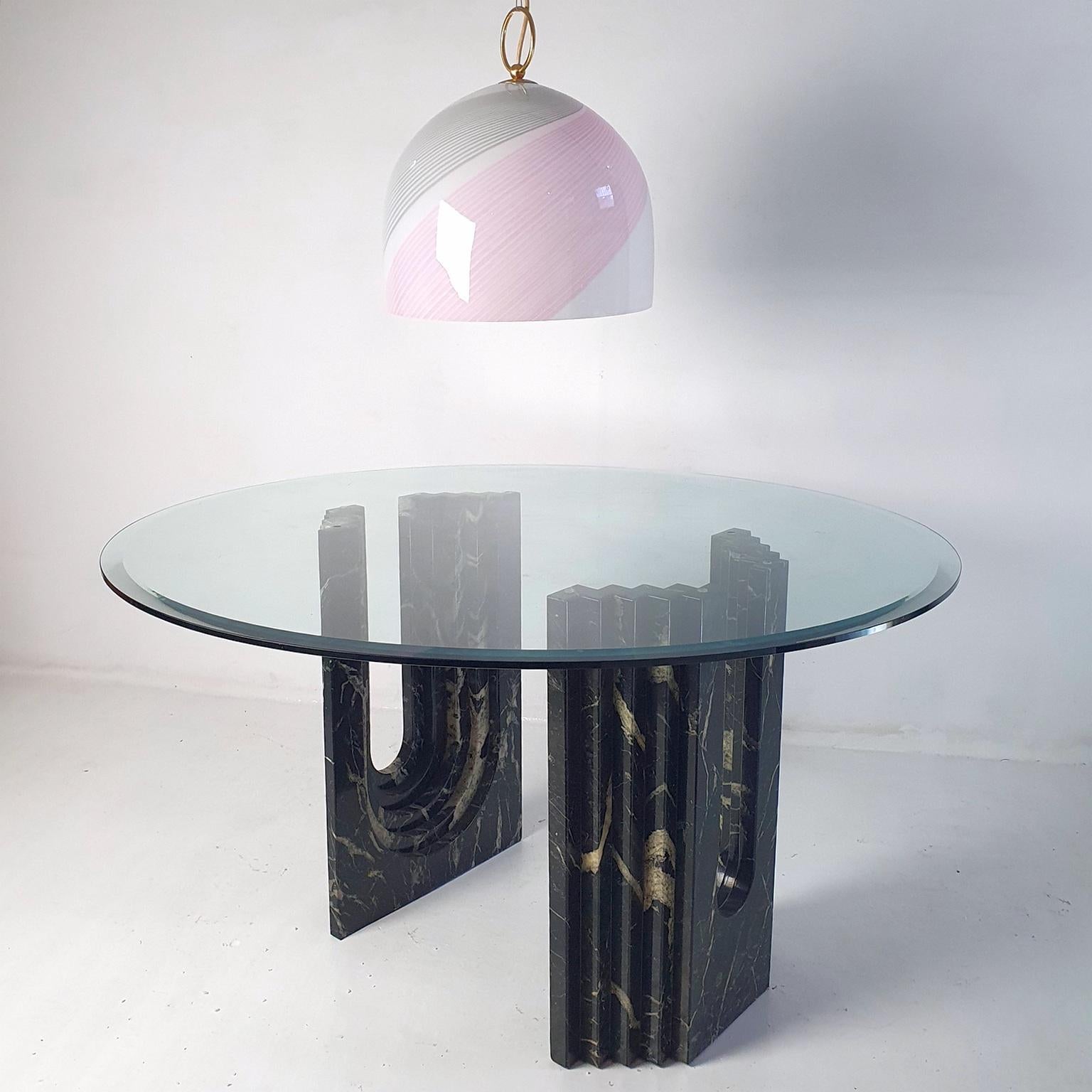 This table was designed by the famous architect and designer Carlo Scarpa for Cattelan Italia in the 1960s, but it was produced in the late 1970s or early 1980s. The leg bases are made of Black Madagascar marble, and the top is the original round