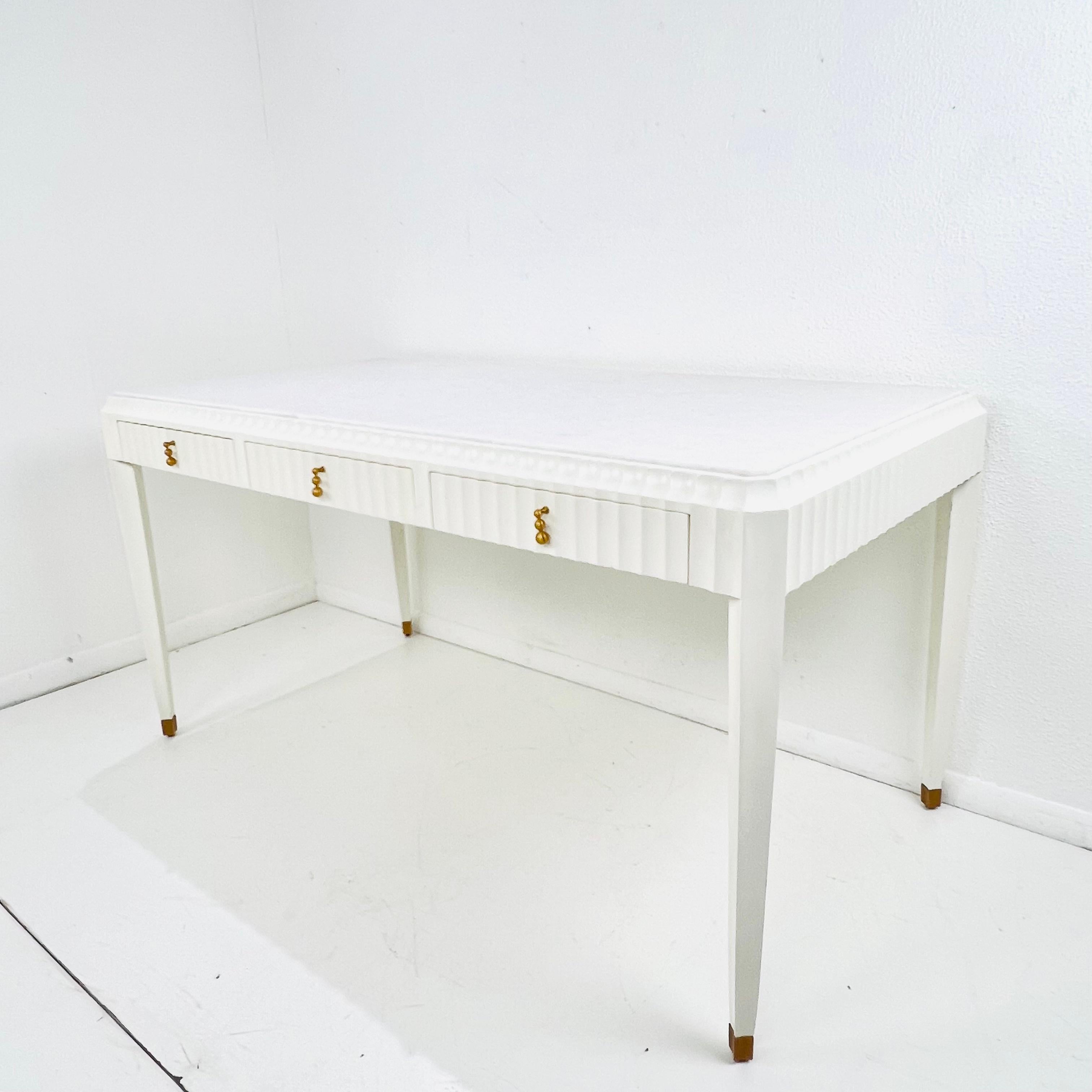 Finished in cream and satin brass, this sophisticated 3 drawer writing desk features a fluted front, honed marble top and hand cast brass pulls. Each drawer has a velvet insert. Designed by Ashley Childers for Global Views. Good structural