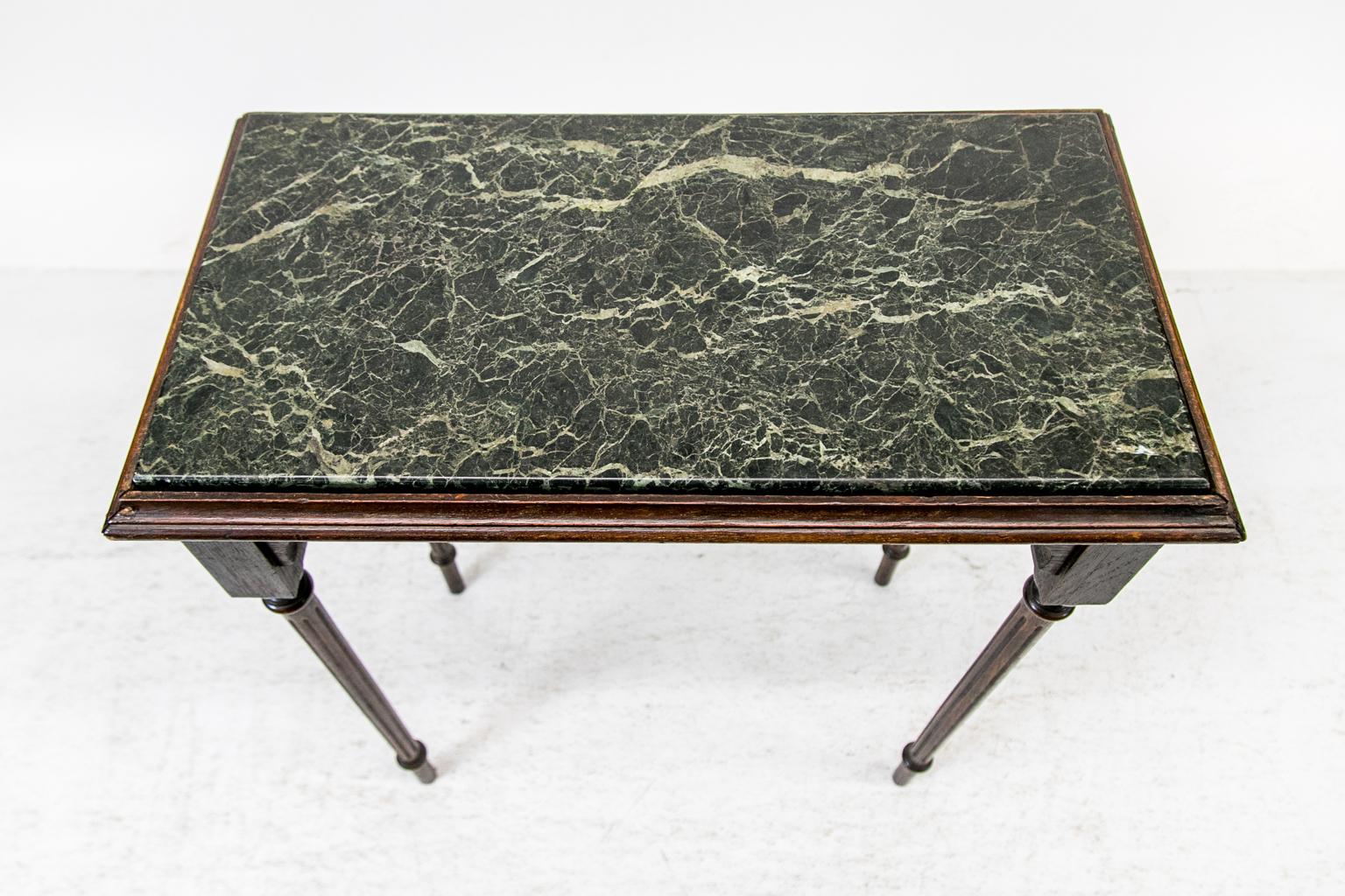 This rectangular center occasional table is finished on all four sides with bracket shaped aprons all around. The removable green marble is framed with a molded top and has four fluted legs.
