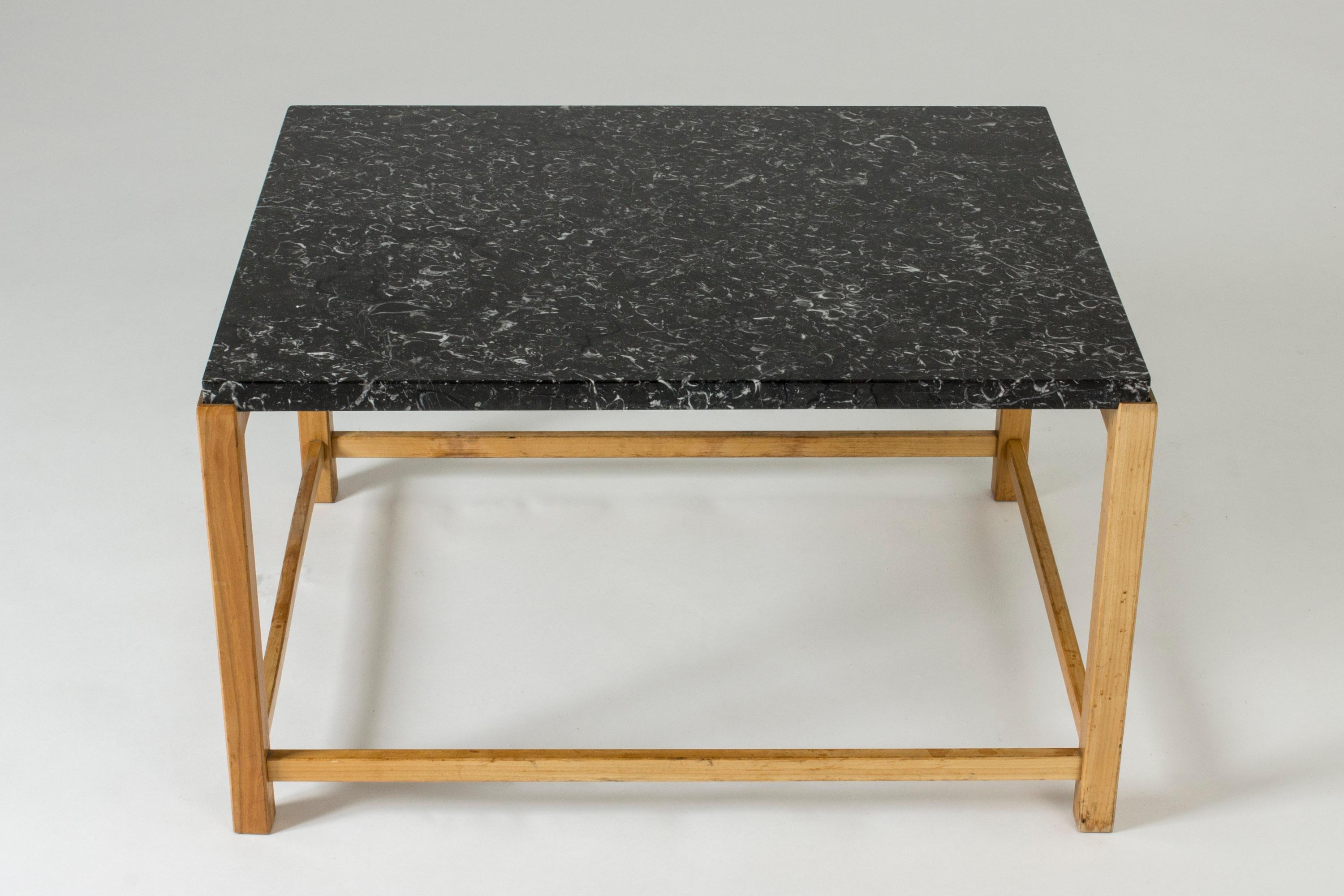 Very cool coffee or occasional table with a strict, open Silhouette and wonderful, lively black marble top. Elmwood base.