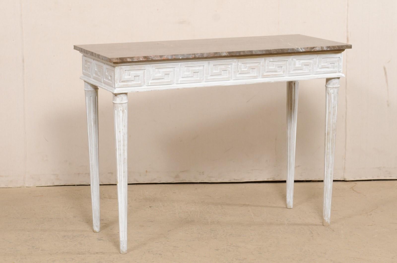 An American marble top console table in Greek key motif. This vintage American console table has a rectangular-shaped marble top which rests upon a skirt with is carved in a Greek key pattern, which continues on all four sides of the table, making