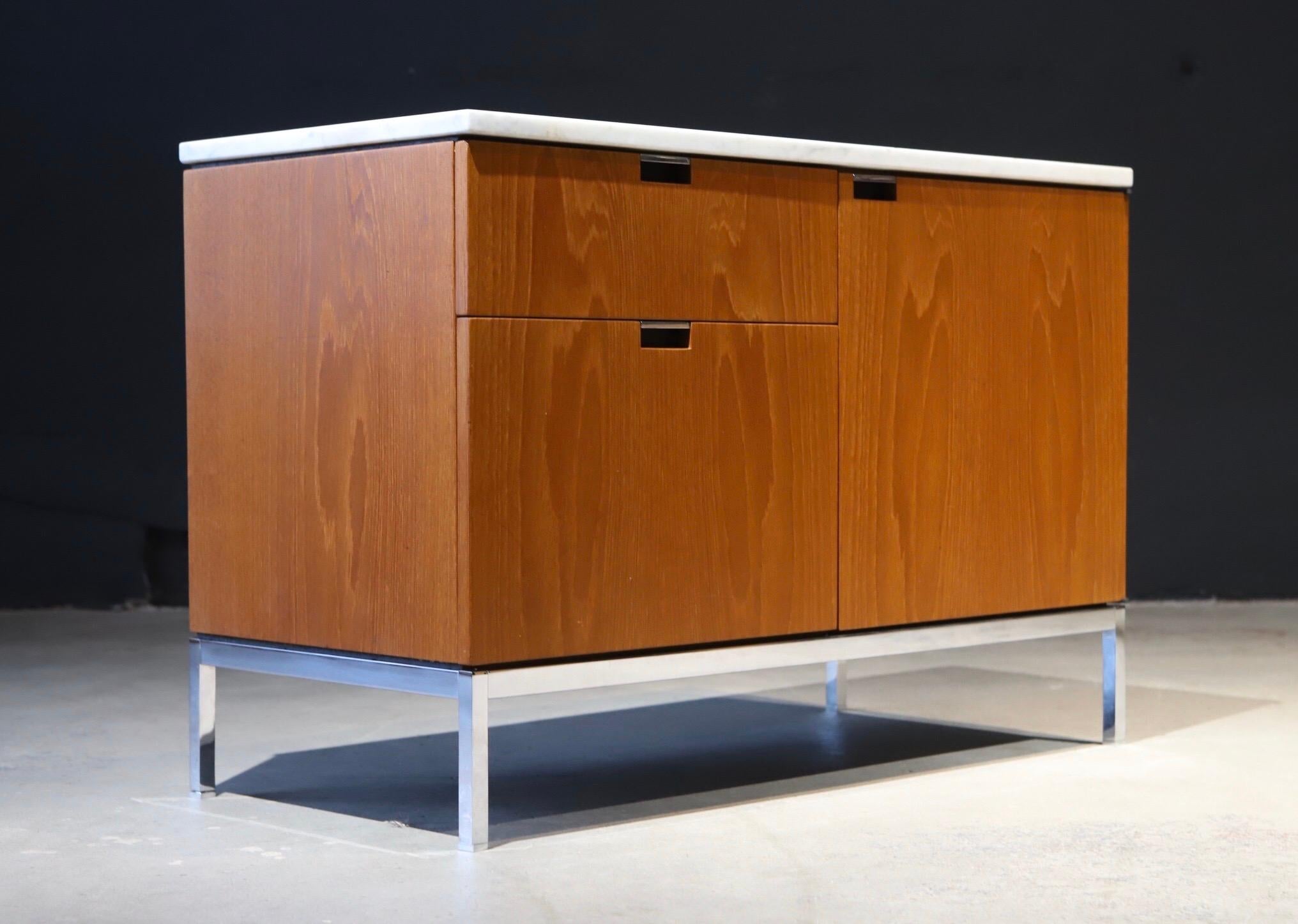 Simplicity in design. A stunning small credenza designed by Florence Knoll for Knoll. Featuring a marble top, chrome base and plenty of storage. Retains all four square metal leveling glides and pen drawer. Pictured with larger Knoll credenza and