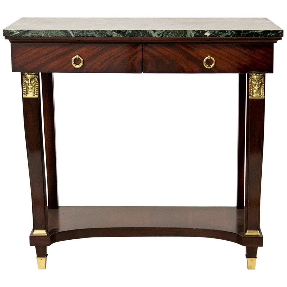 Marble-top English Regency style console table, with the drawers having book matched flame grain mahogany. The curved front legs have Egyptian head motifs at the top and brass bases at the bottom, which extend to tapering feet with brass cups.
  