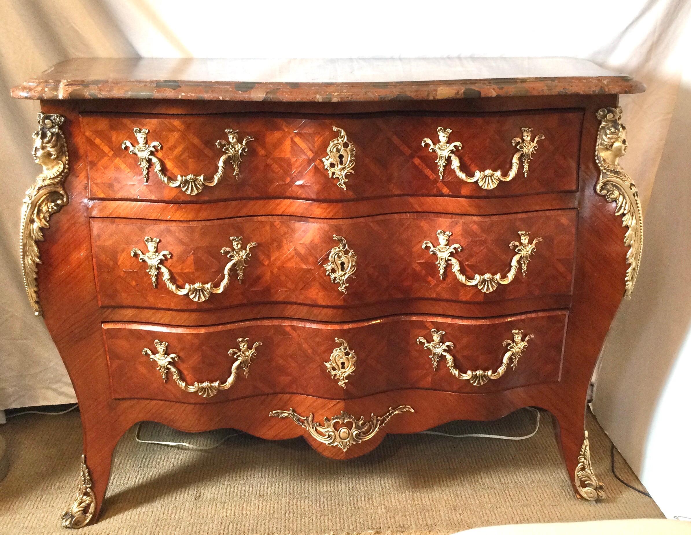 A French three drawer bombe chest with parquetry inlay. The shapely front with cast bronze mounts and original rouge marble.