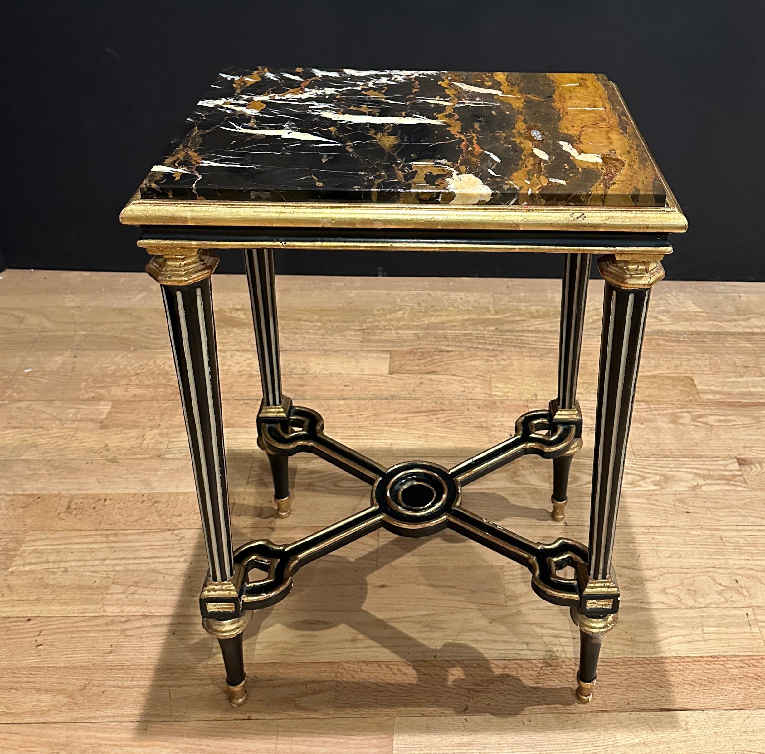 Gilt and ebonized marble top side table. Unusual black, gold and white merle top. Tapered and fluted carved legs with an X- form stretcher.