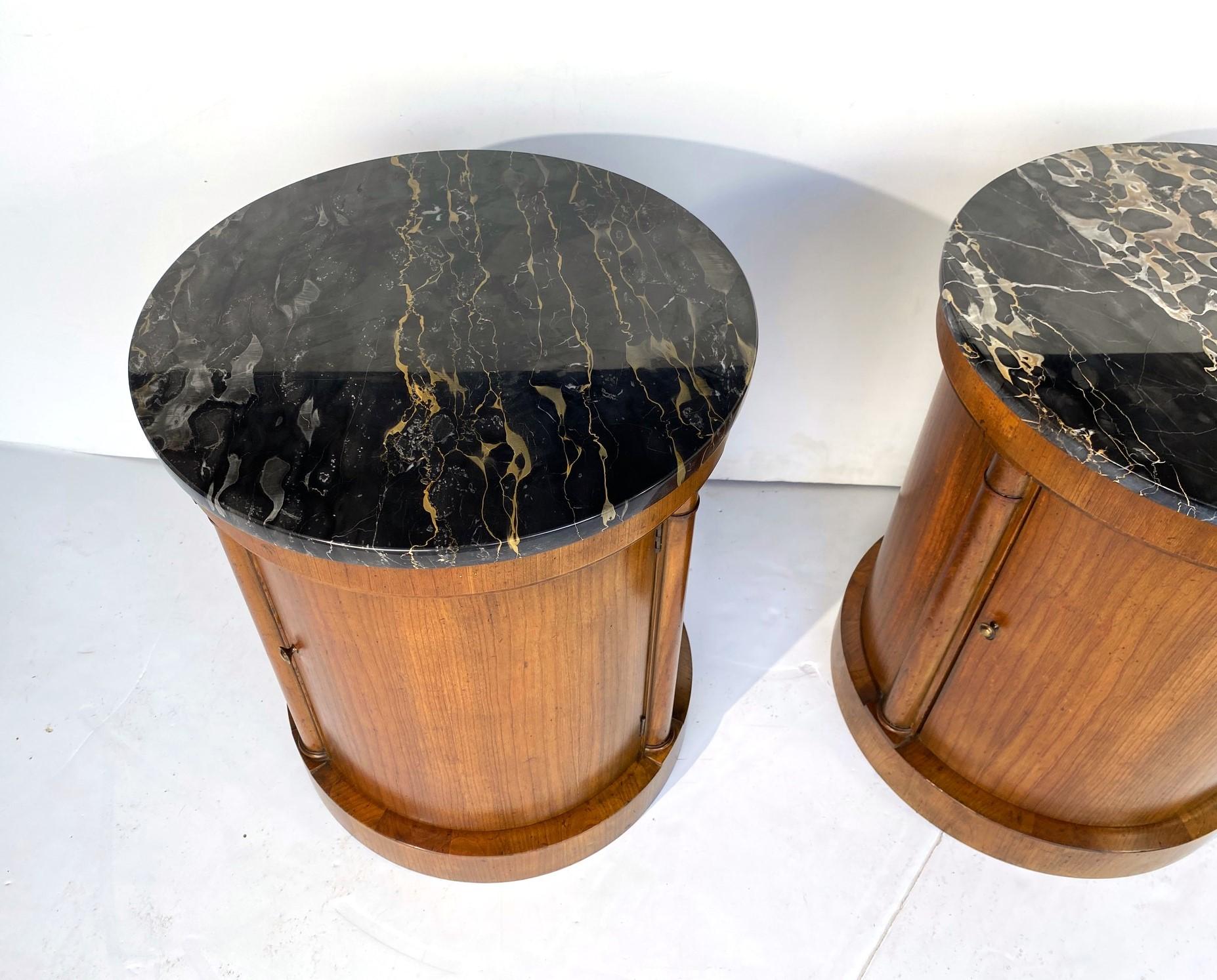 A pair of round-shaped marble top nightstands by Baker. Single door with a single shelf.