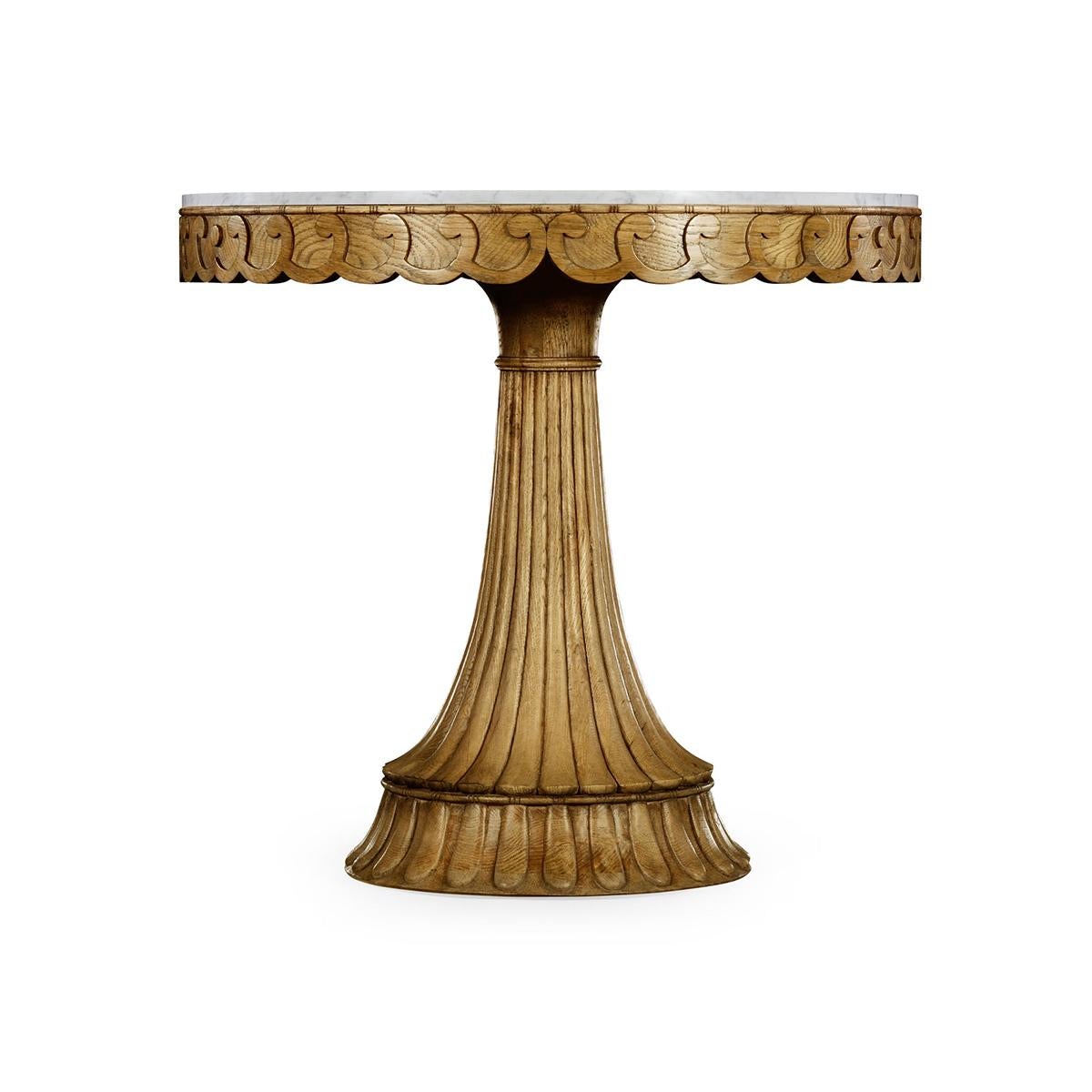 A Scottish style carved oak round center table with an Italian Carrara marble top, carved vetruvian scroll work frieze, and out flaring fluted pedestal base. 

Dimensions: 35.5