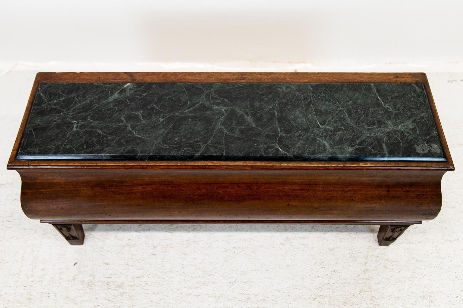 This English marble top bench / table has a verde marble top with a bombay shaped front and sides that terminate in carved tapered legs. The interior is hollow.