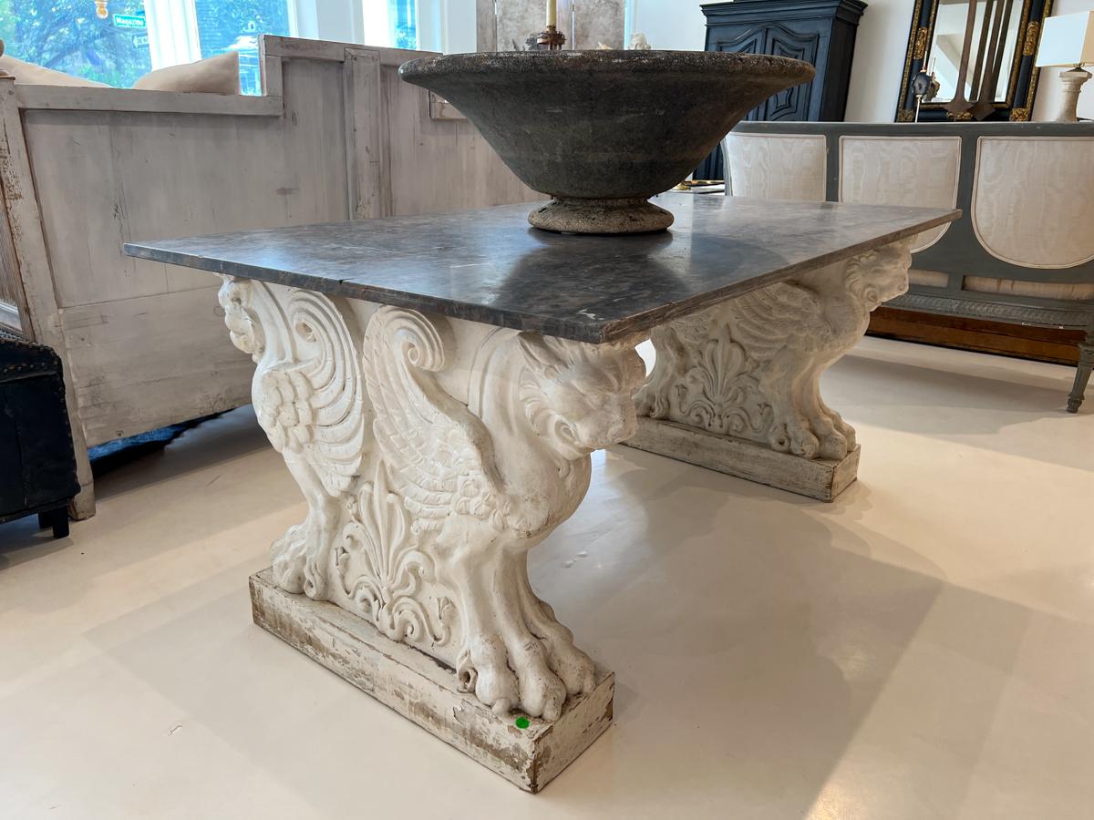 Beautiful piece of black marble with specks of red, taupe and white. The base is two dramatic columns featuring back to back griffons.